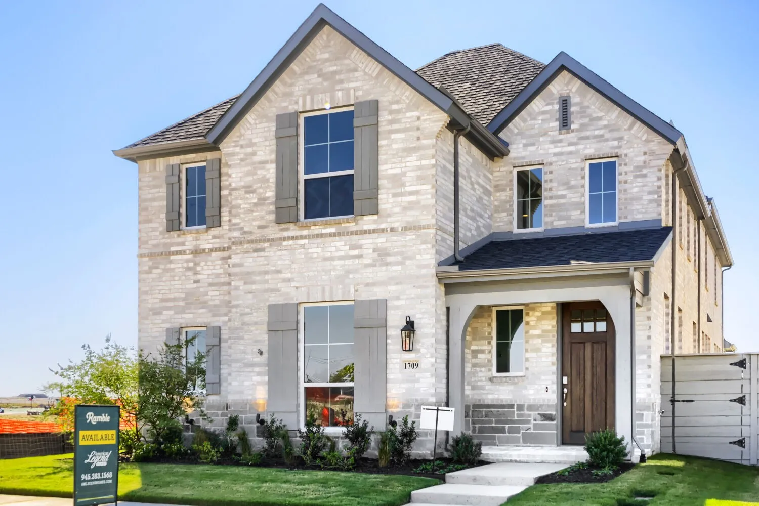 Striking two-story residence featuring a light-hued stone exterior, arched entryway with wood-finish door, and multi-pane windows across both levels