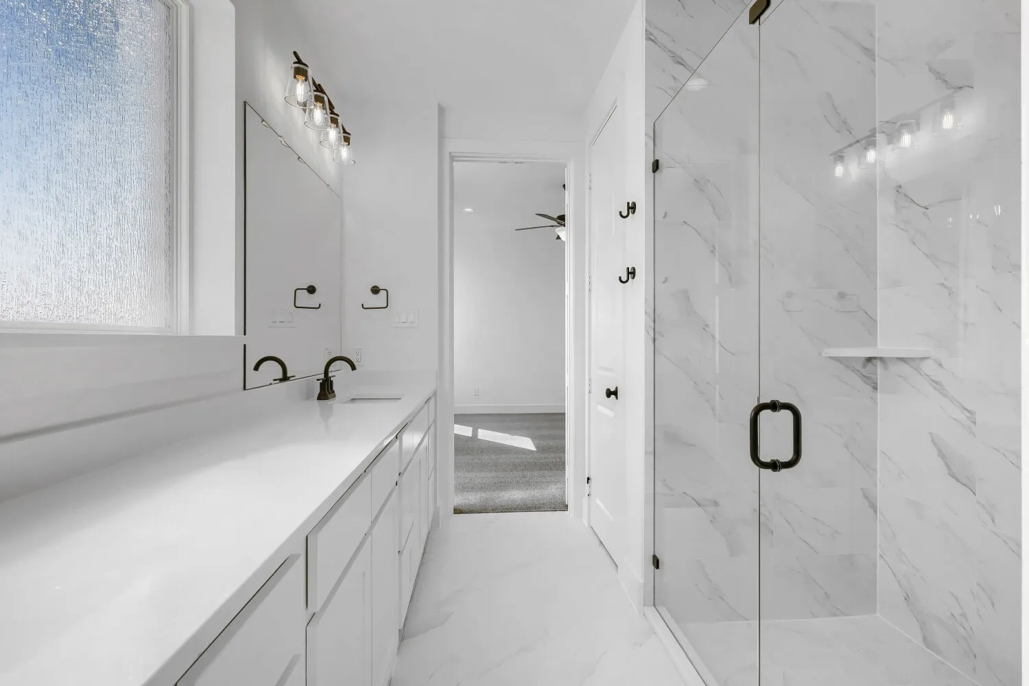 Dual vanity with white countertops, undermount sinks, and dark-finished fixtures