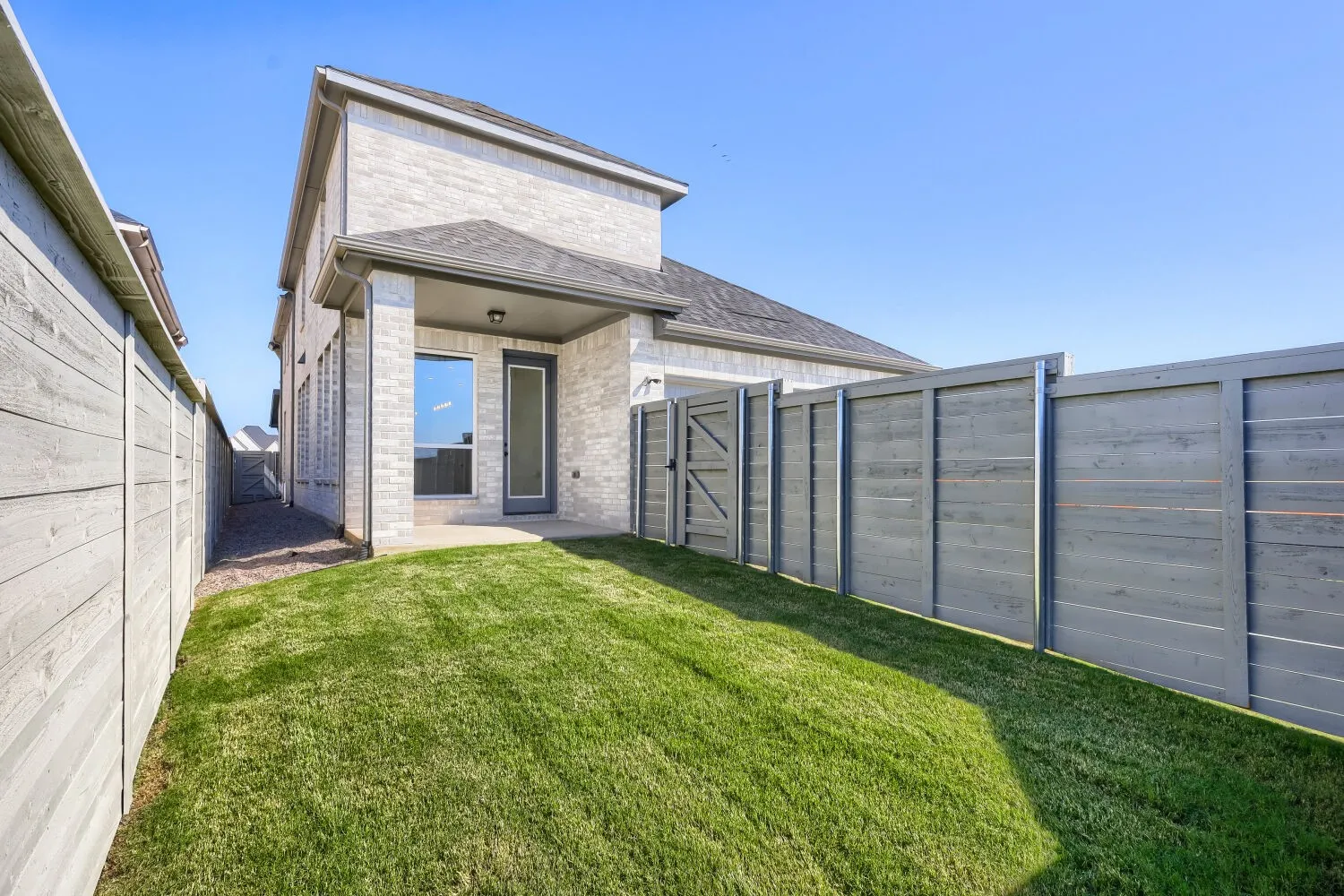 Spacious backyard with lush, manicured lawn and modern composite fencing
