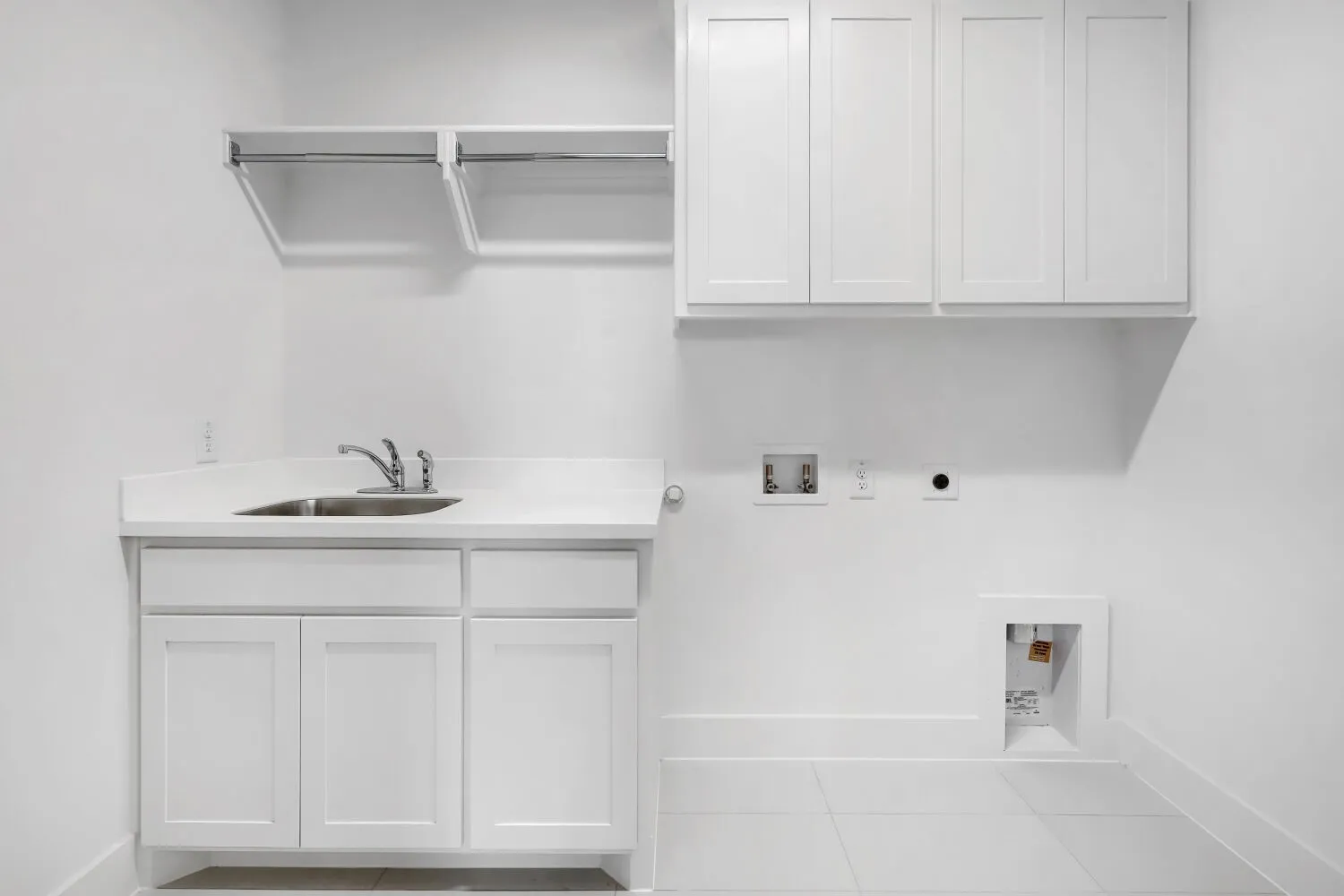 White shaker cabinetry, utility sink, chrome faucet, and tile flooring