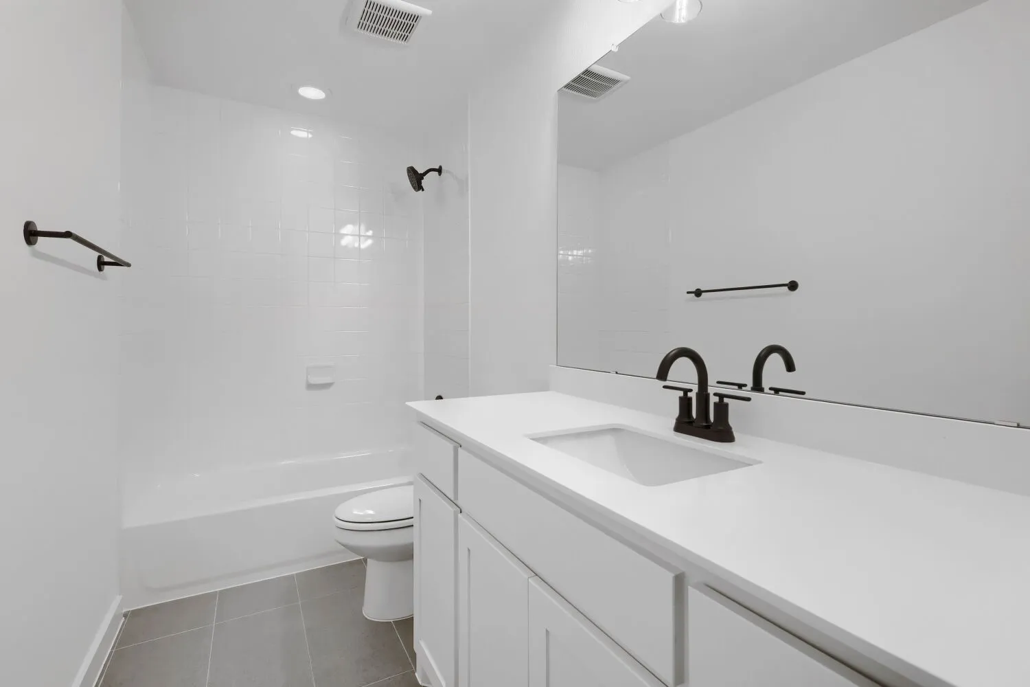 White vanity with a large rectangular sink, wide mirror, and matte black fixtures