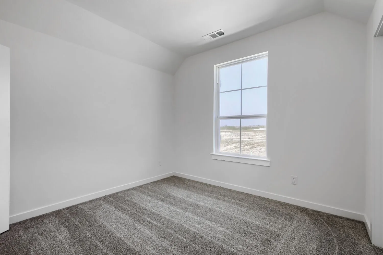 Gray carpeted flooring, white walls, and a window with white trim