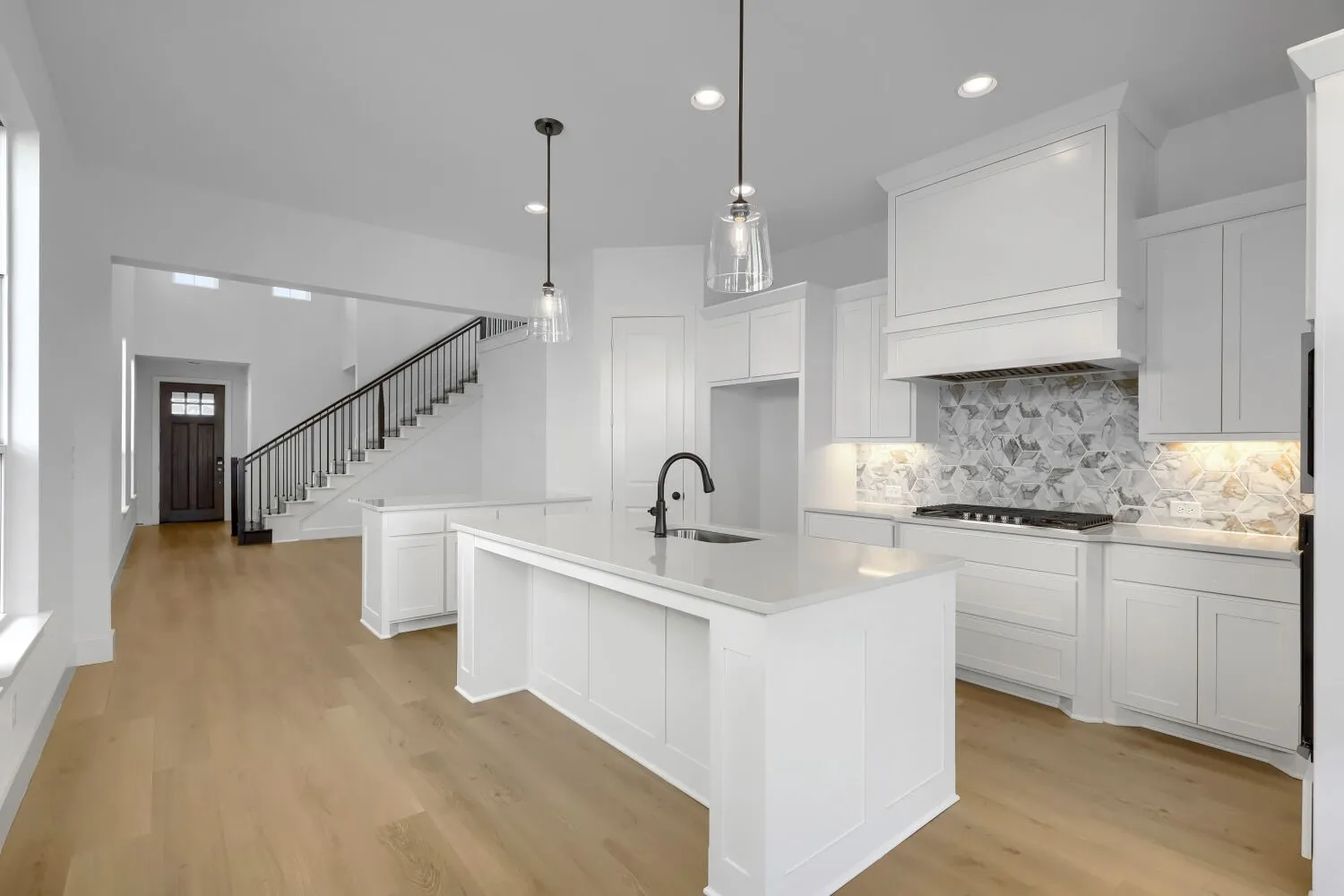 Expansive kitchen featuring white cabinetry, quartz countertops, and a patterned tile backsplash