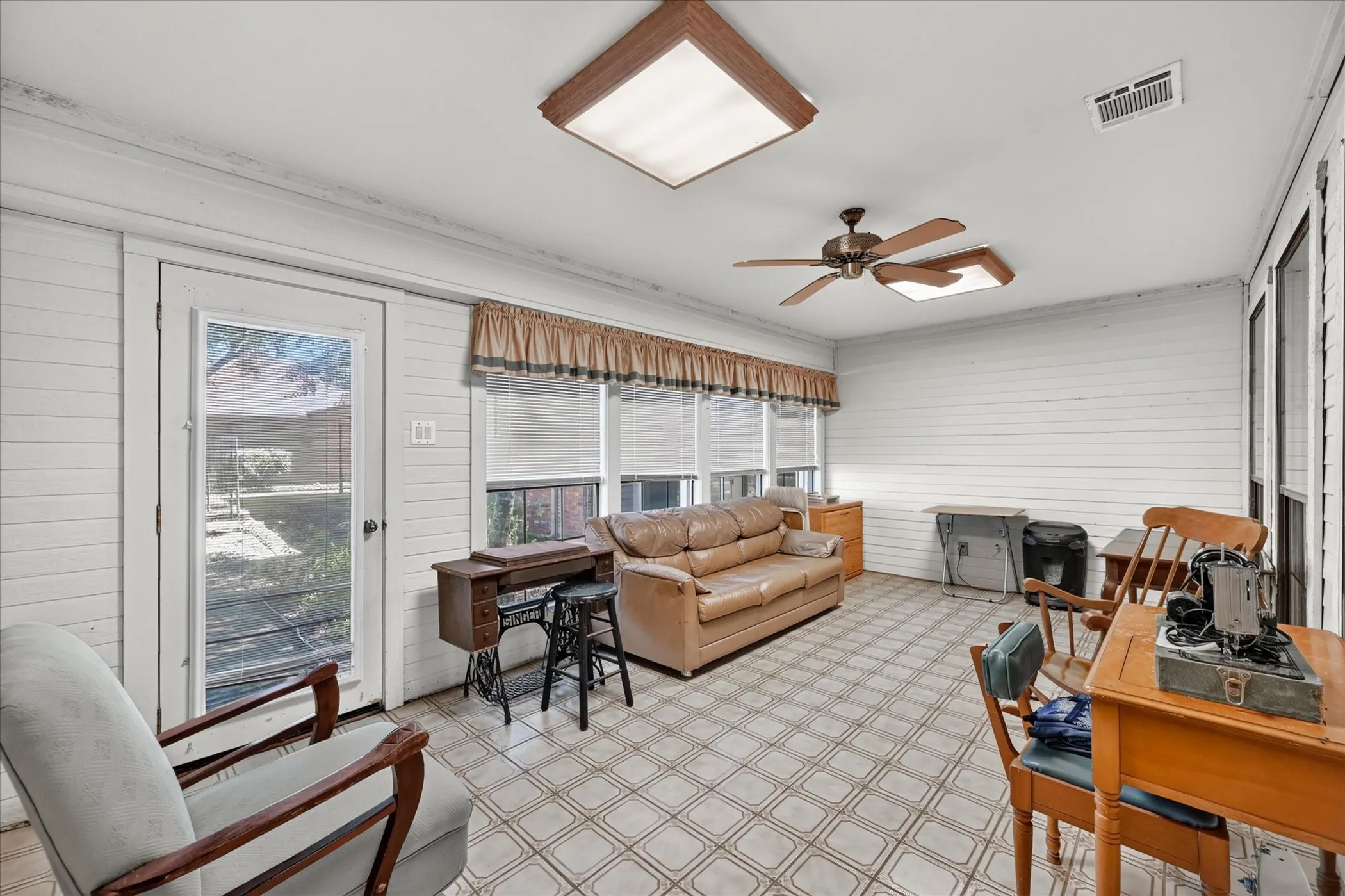Floor-to-ceiling windows with blinds, patterned tile flooring, ceiling fan, recessed lighting, and a glass-paneled door