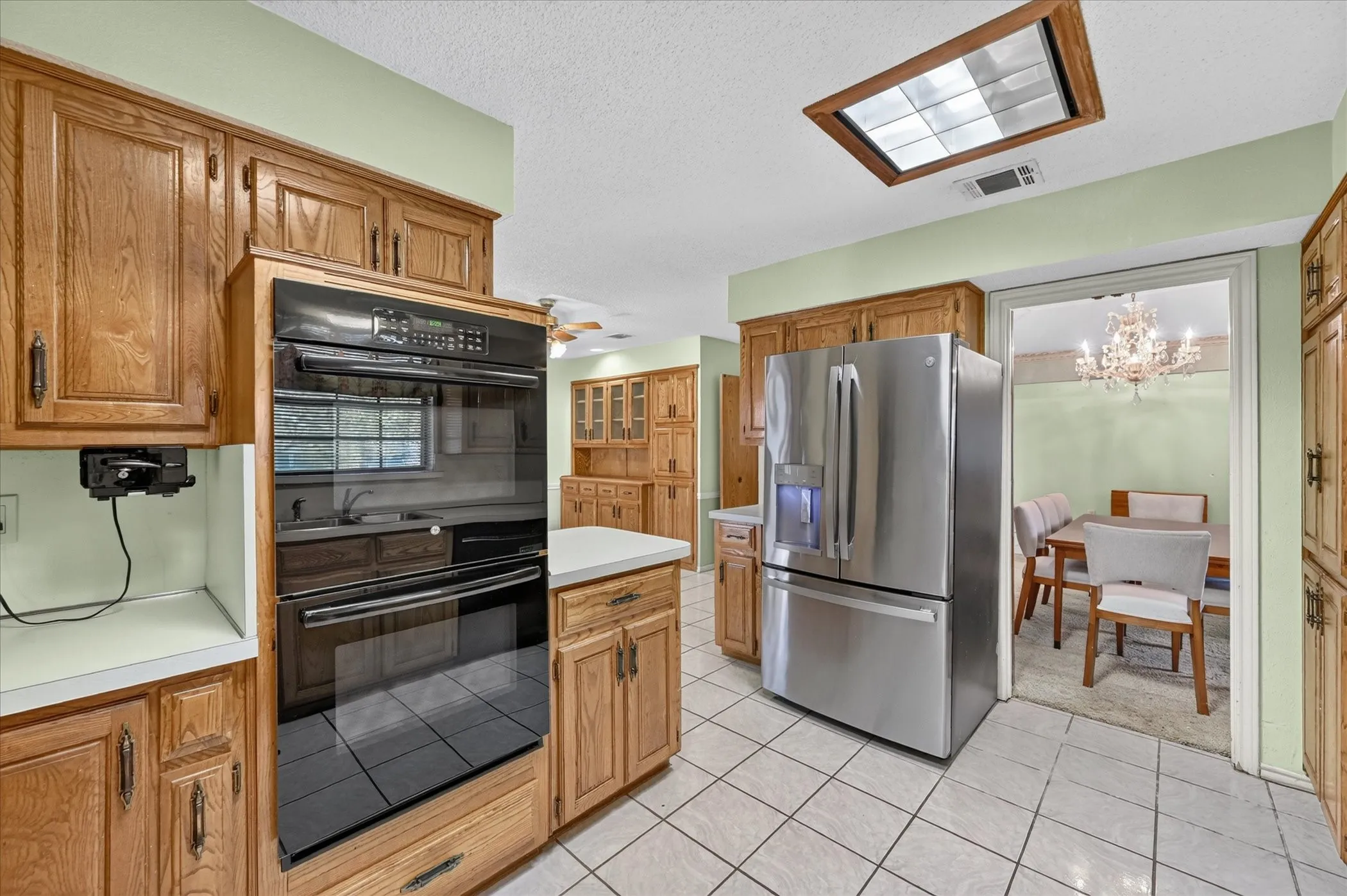Kitchen featuring wood cabinetry, stainless steel refrigerator, built-in double oven, and tiled flooring