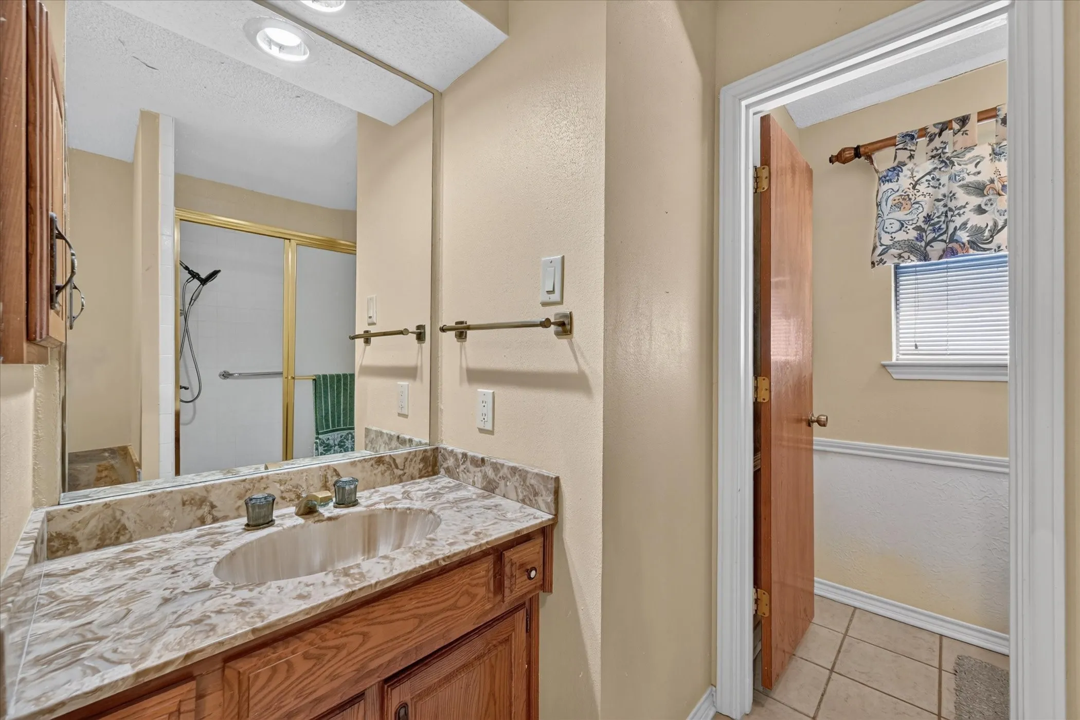 Wood-finish vanity with an oval basin sink and a stone countertop