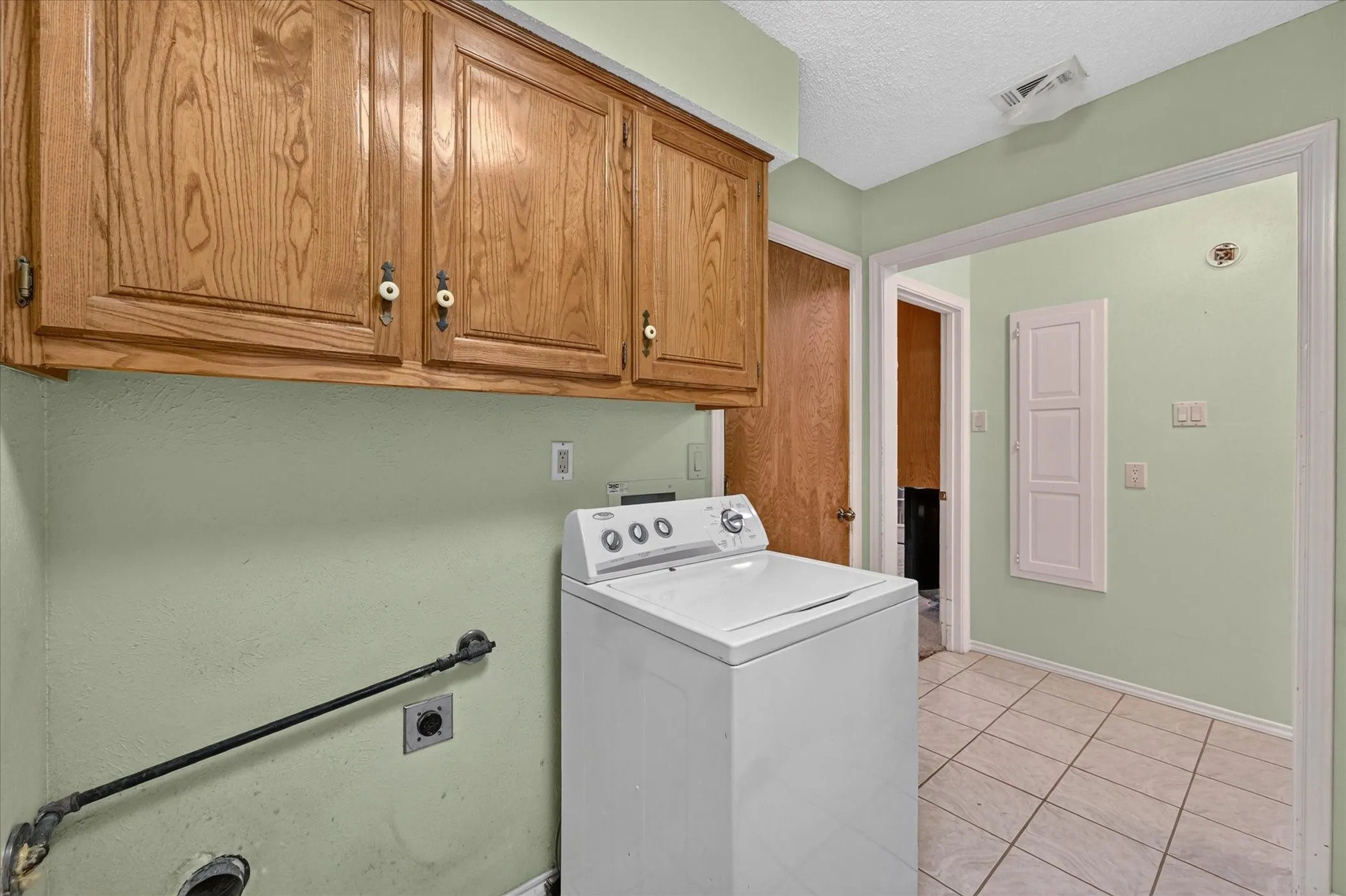 Built-in wood cabinetry with decorative pulls, tile flooring, and light green wall finish