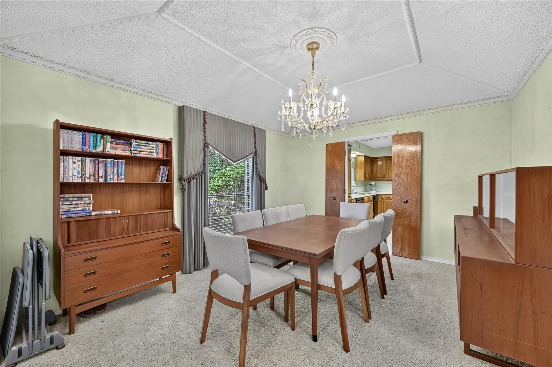 Textured ceiling with decorative molding, chandelier lighting, and double bi-fold doors