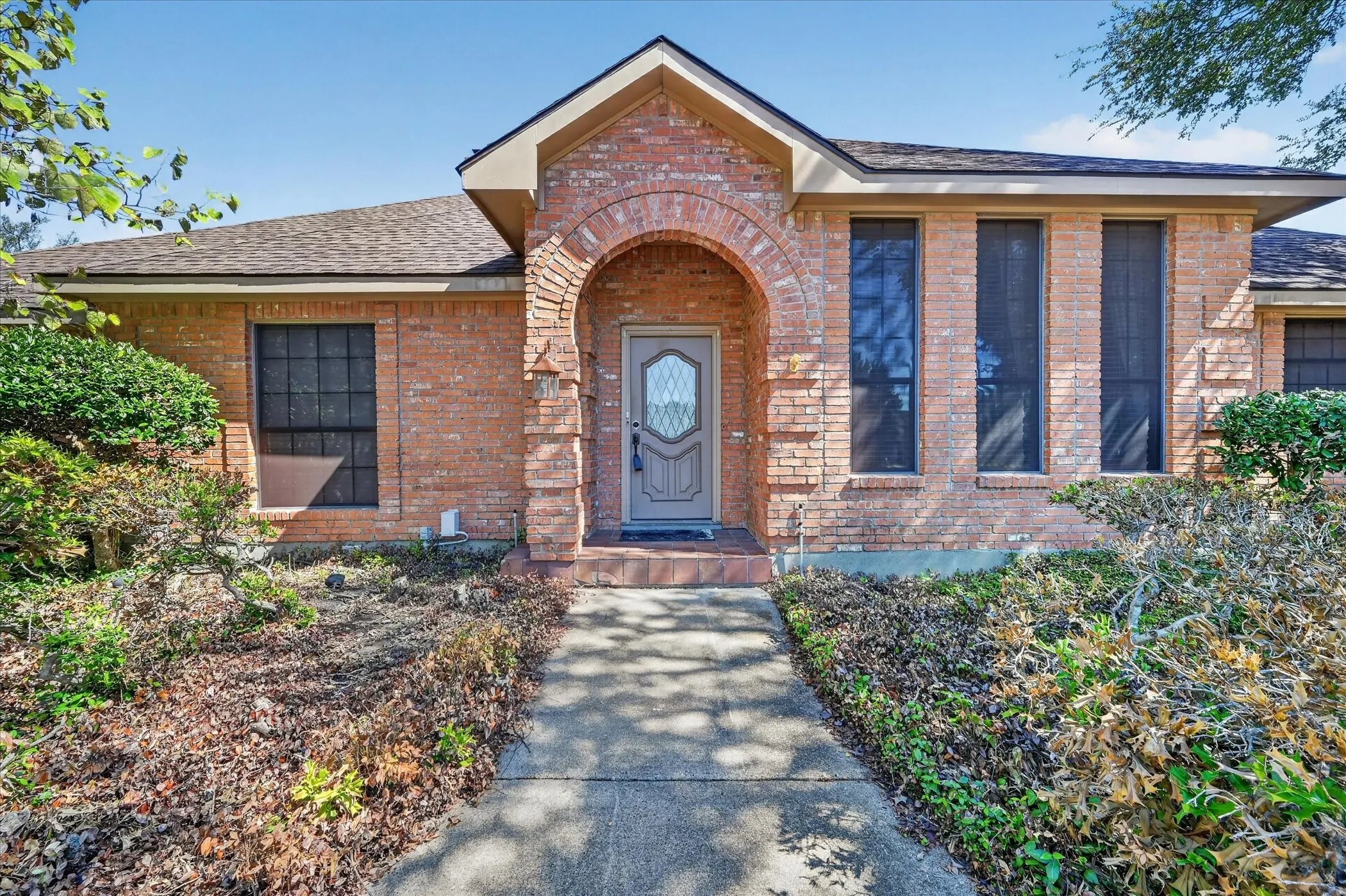 Brick facade with an arched entry, a decorative glass-paneled door, and multiple large windows