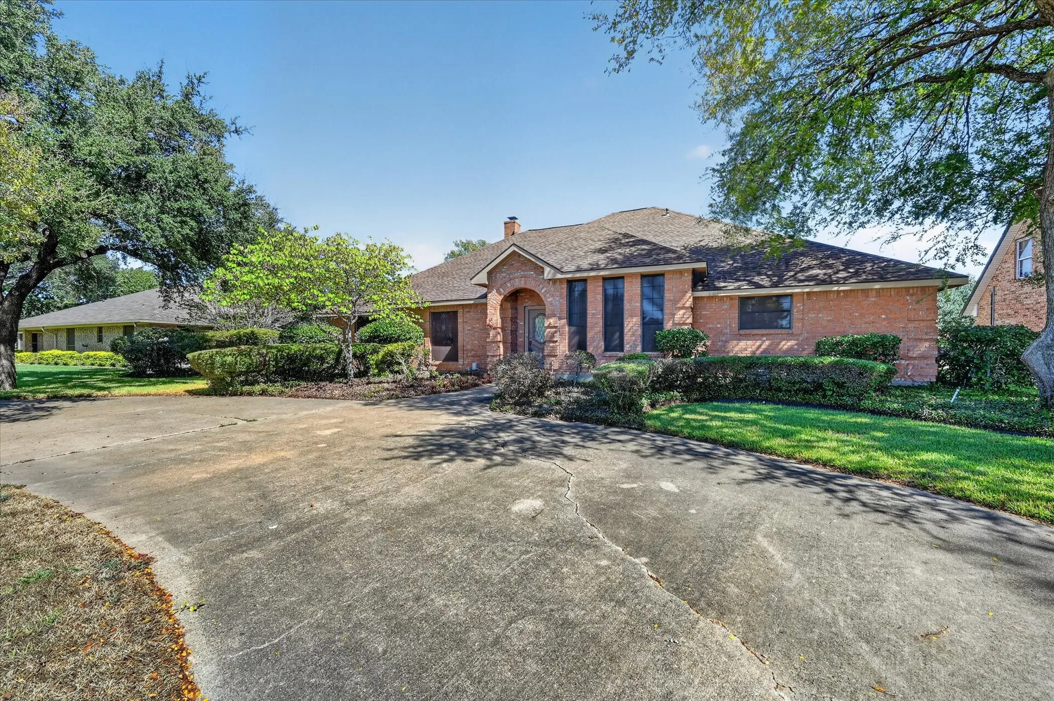 Brick exterior with a gabled roof and mature trees