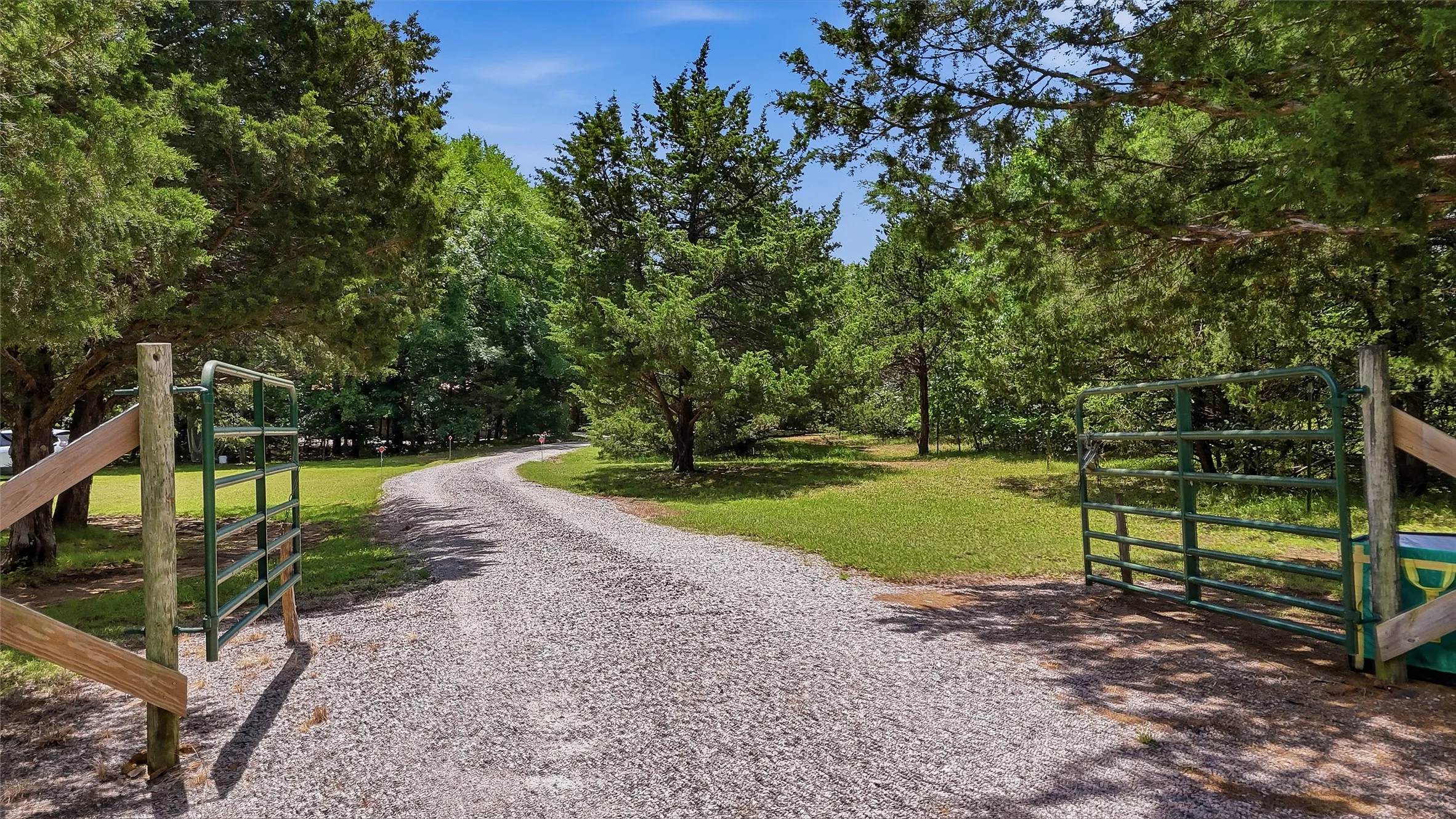 Gravel drive with a metal gate and mature trees