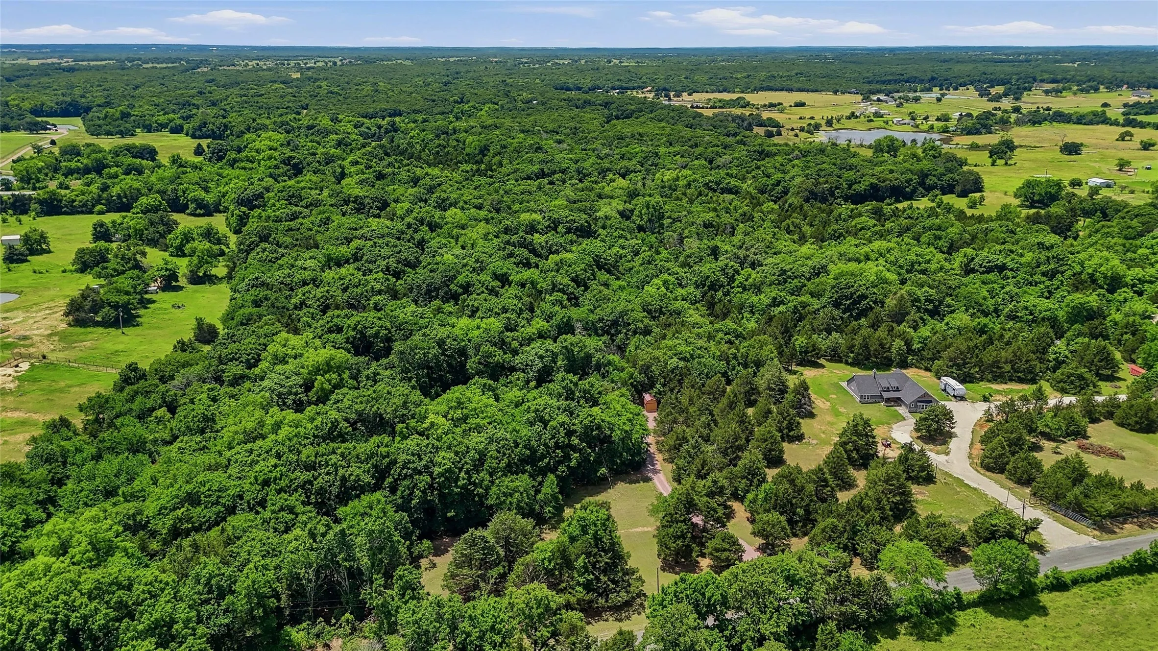 Expansive treed acreage with a single-story residence and a private driveway
