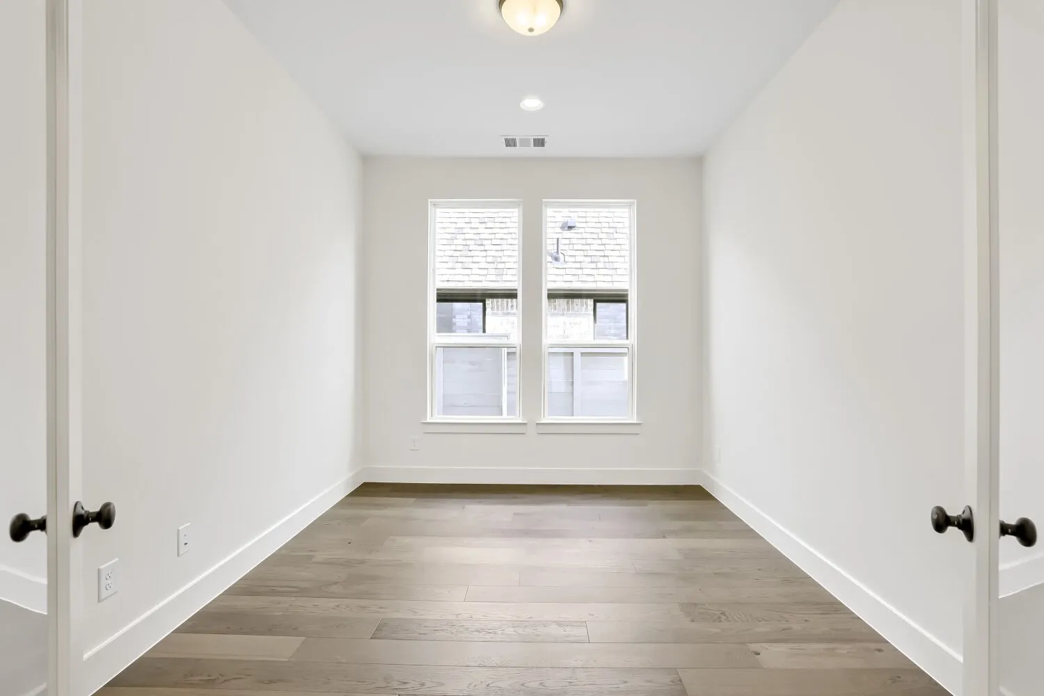 Wood-finish flooring, white walls, double windows, recessed lighting, and a flush mount ceiling fixture
