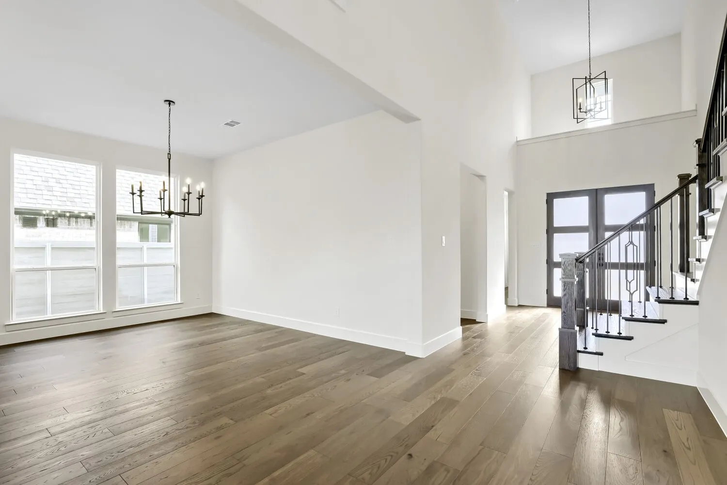 Wood-finish flooring throughout, with a grand entryway featuring a two-story ceiling and contemporary lighting