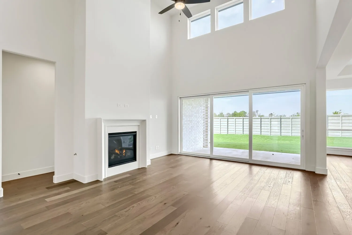 Two-story ceiling, built-in fireplace, wood-finish flooring, sliding glass patio doors, and high-set transom windows