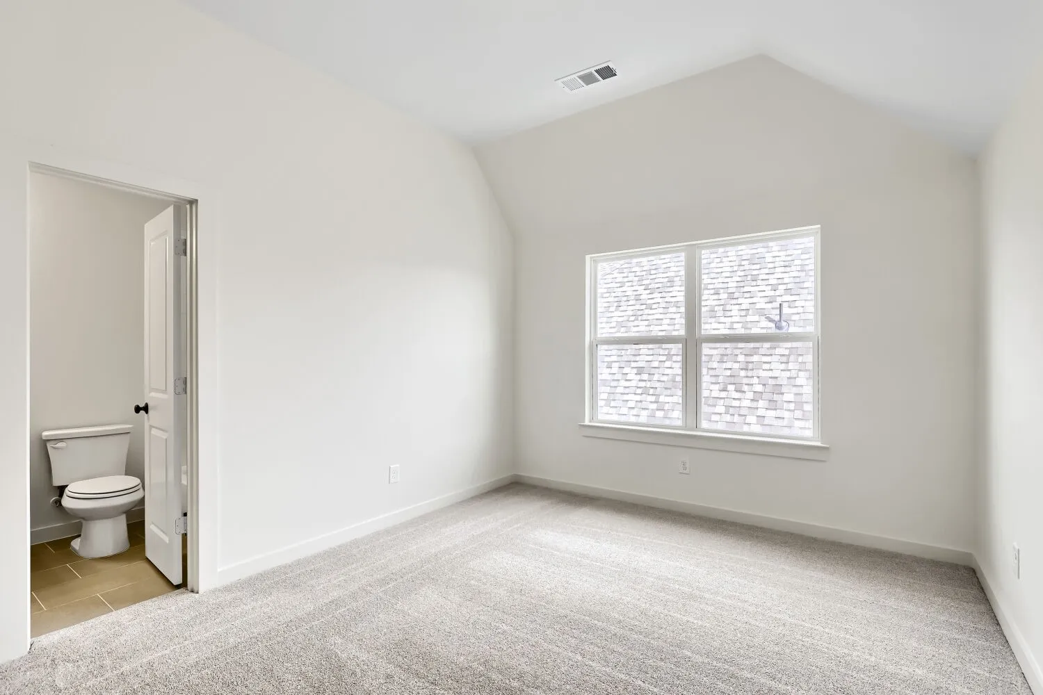 Vaulted ceiling, carpeted flooring, large window, interior door, and a built-in toilet