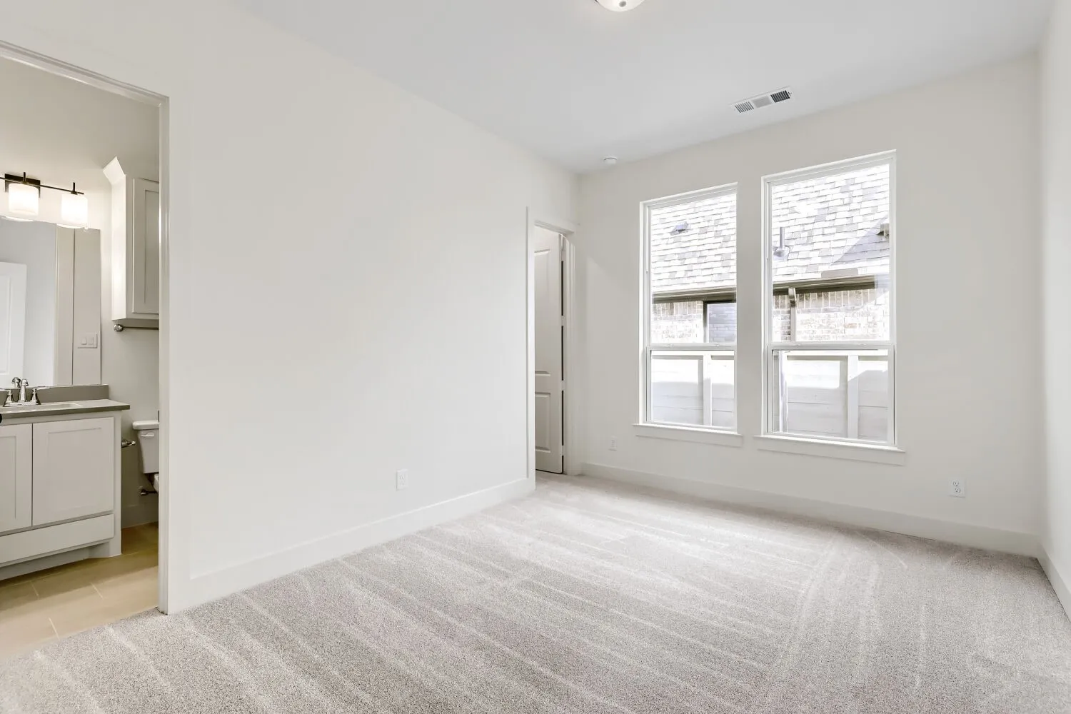 Carpeted room with double windows, a white paneled door, and recessed lighting