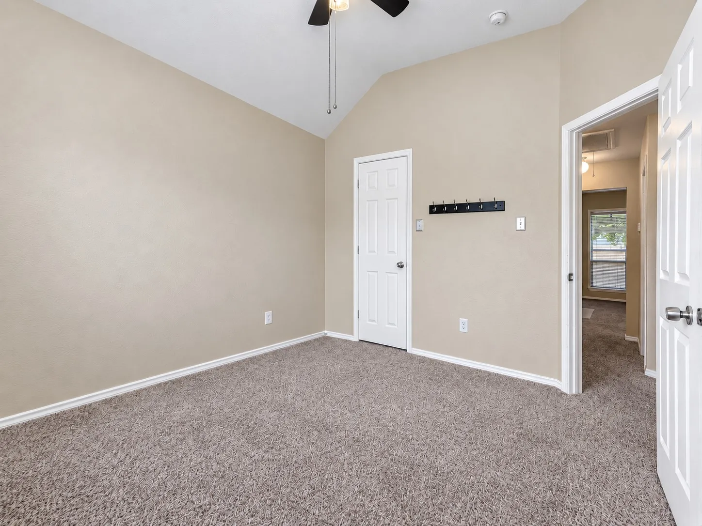 Vaulted ceiling with a ceiling fan, neutral carpet flooring, and white trim