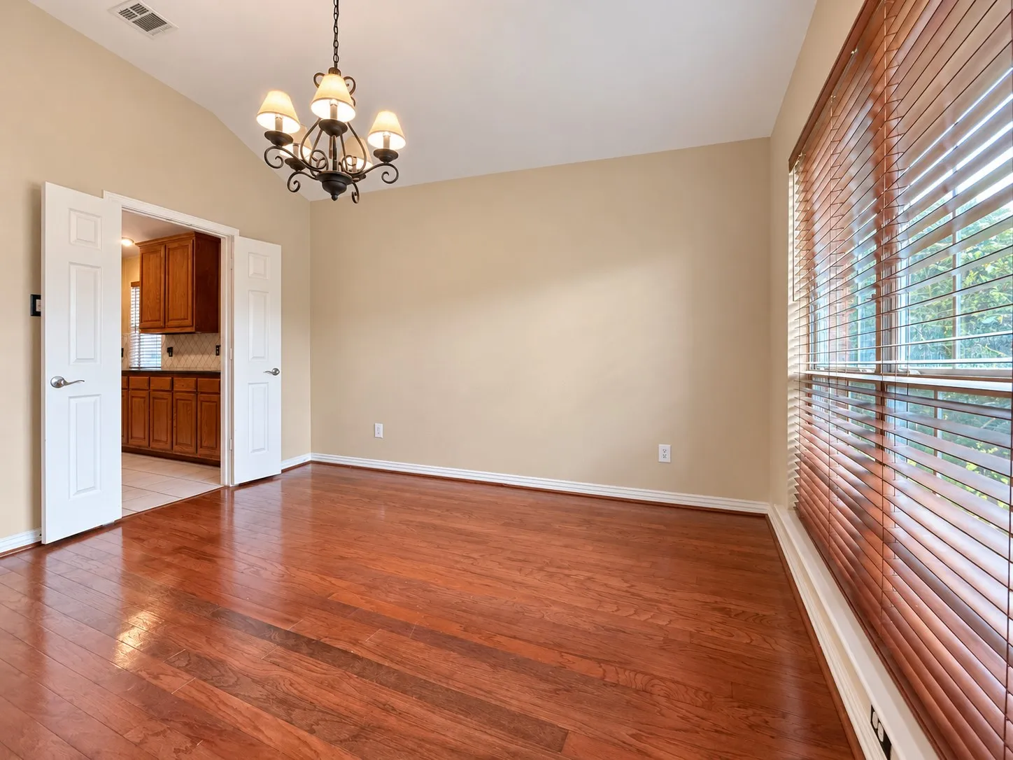 Wood-finish flooring, vaulted ceiling, and a five-light chandelier