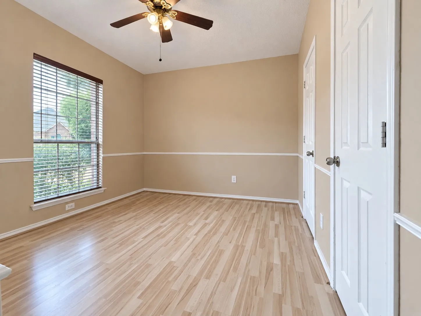 Wood-finish flooring, ceiling fan with integrated lighting, window with blinds, and paneled doors