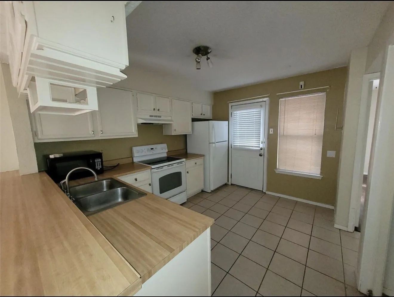 Kitchen featuring white cabinetry, wood-finish countertops, stainless steel double-basin sink, and tile flooring