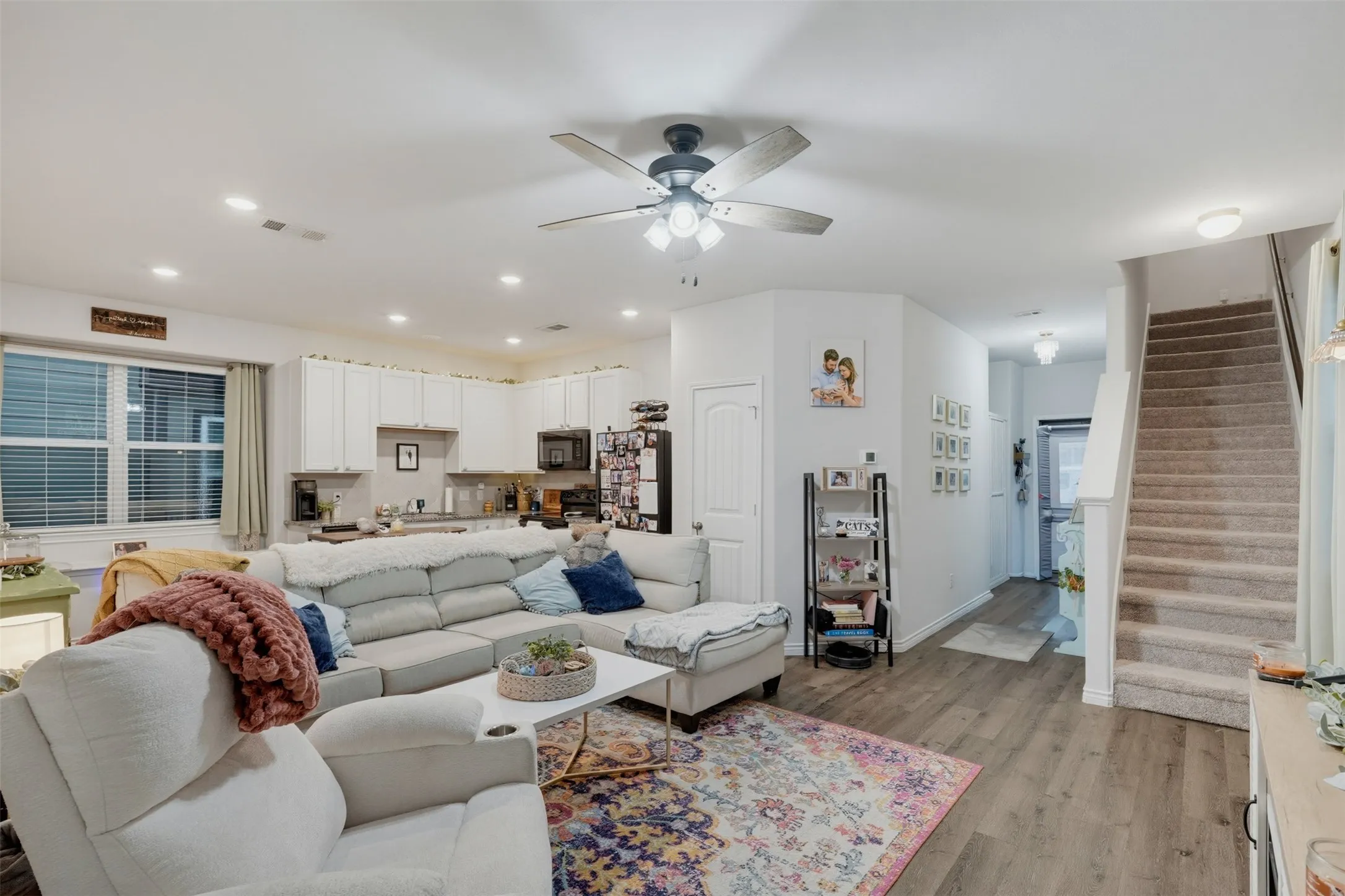 Open-concept living area with wood-finish flooring, a ceiling fan with integrated lighting, and recessed lighting