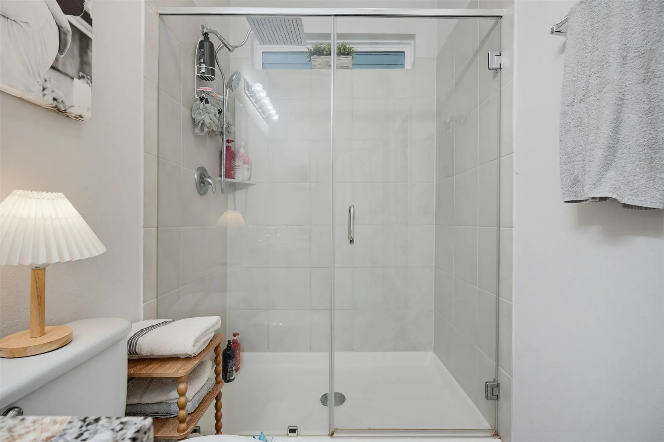 Glass-enclosed shower with white tiled walls and a white shower pan