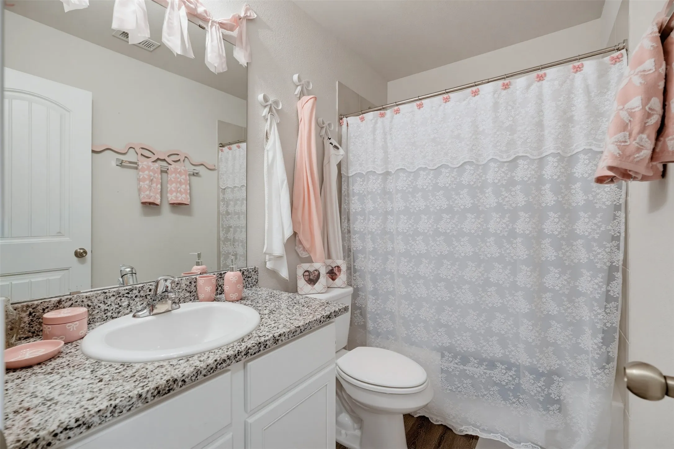 Bathroom featuring a single vanity with a granite countertop, undermount sink, and chrome faucet