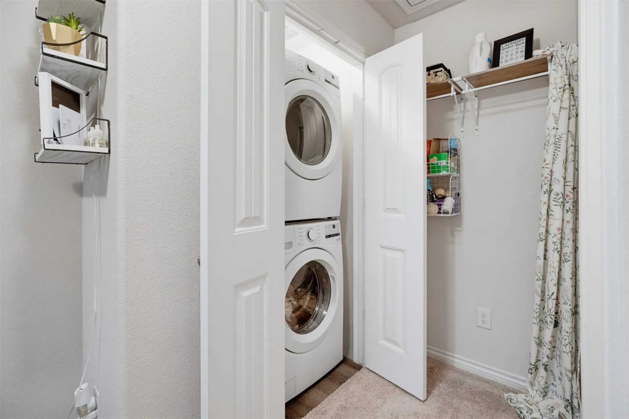 Enclosed laundry area featuring stacked front-load washer and dryer units