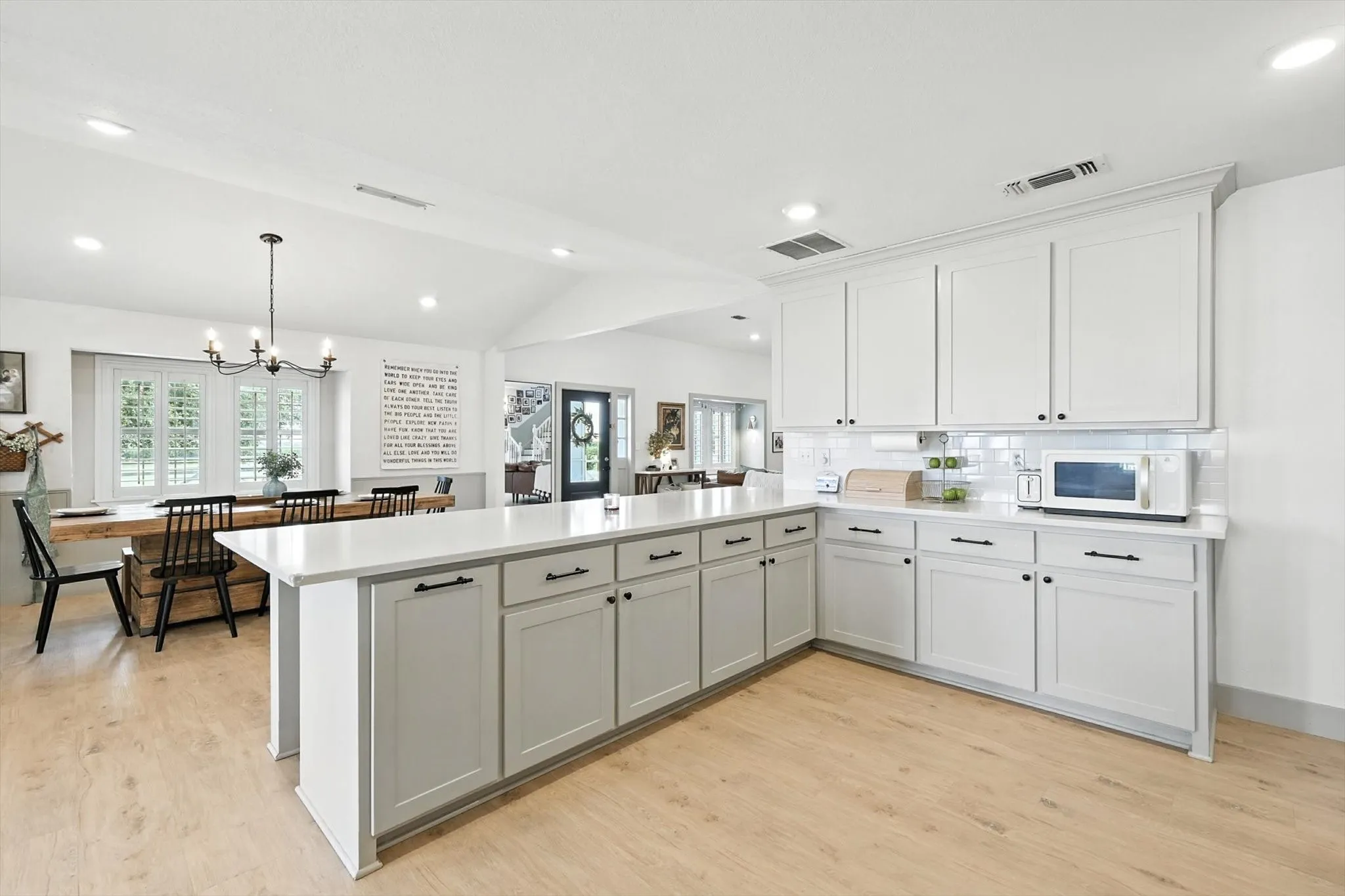 Spacious kitchen featuring white shaker-style cabinetry, light countertops, and a white subway tile backsplash