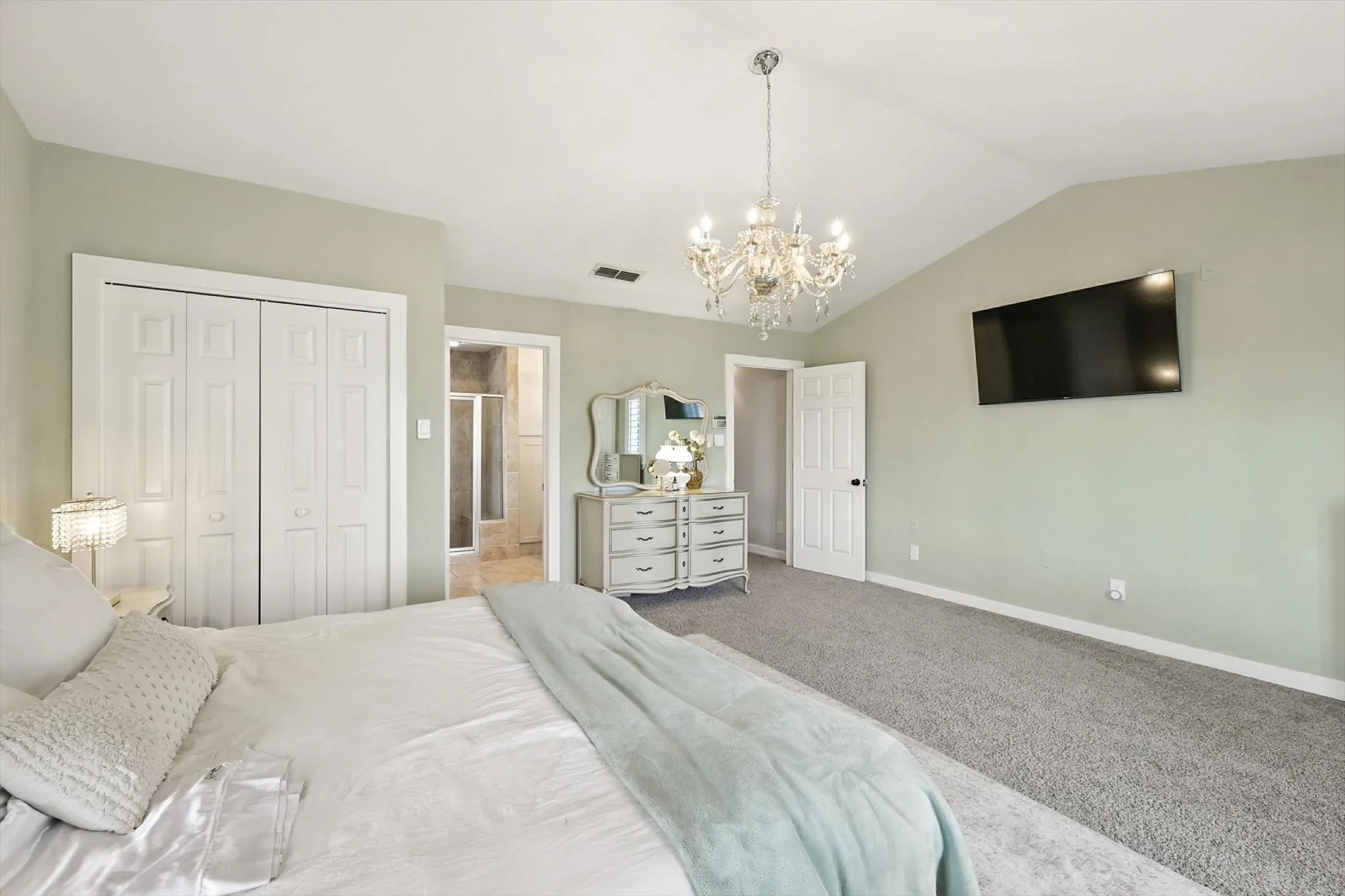 Vaulted ceiling, crystal chandelier, and neutral wall paint