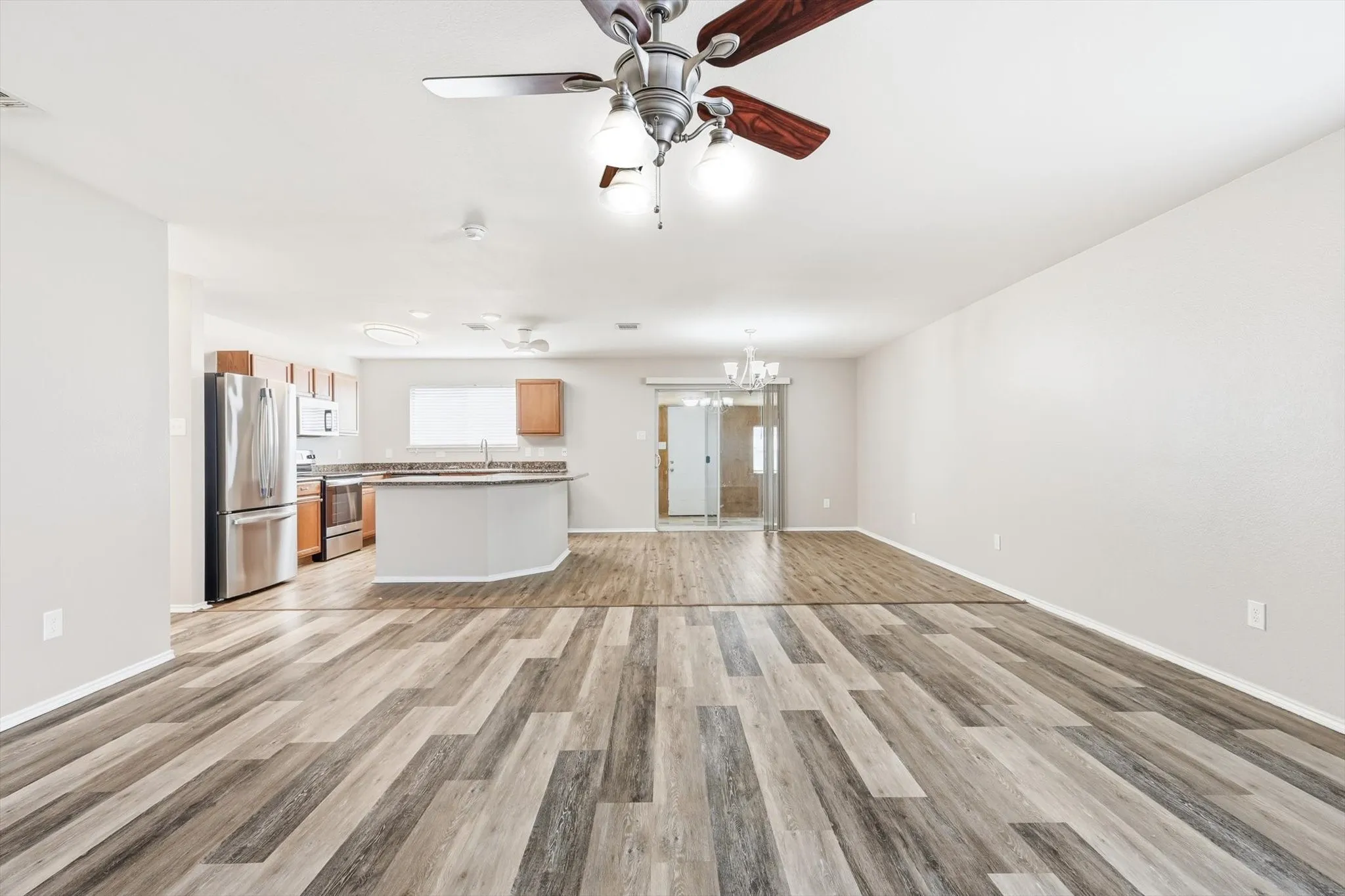 Spacious open-concept living area featuring wood-finish flooring, recessed lighting, and a ceiling fan