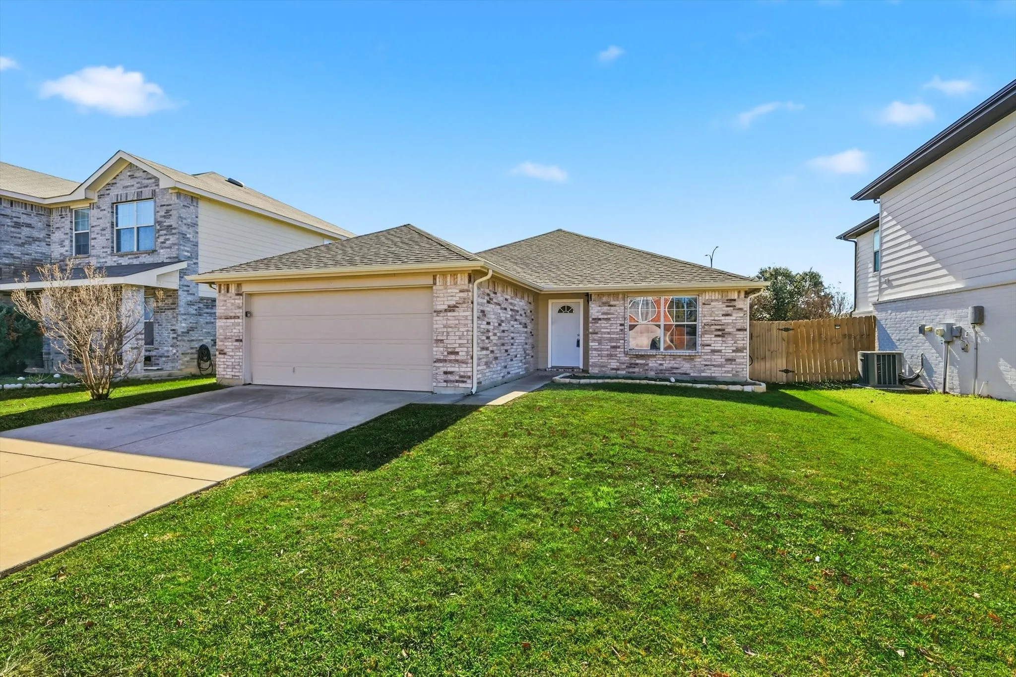 Single-story residence featuring a brick and stone exterior, an attached two-car garage, and a concrete driveway