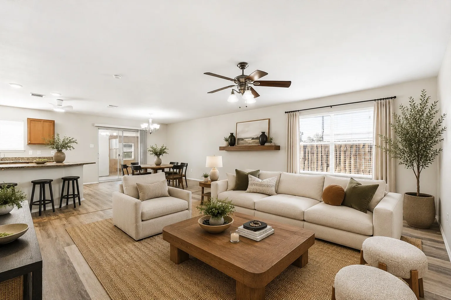 Wood-finish flooring throughout, featuring a ceiling fan, window with blinds and drapes, and a kitchen bar with a stone-finish countertop
