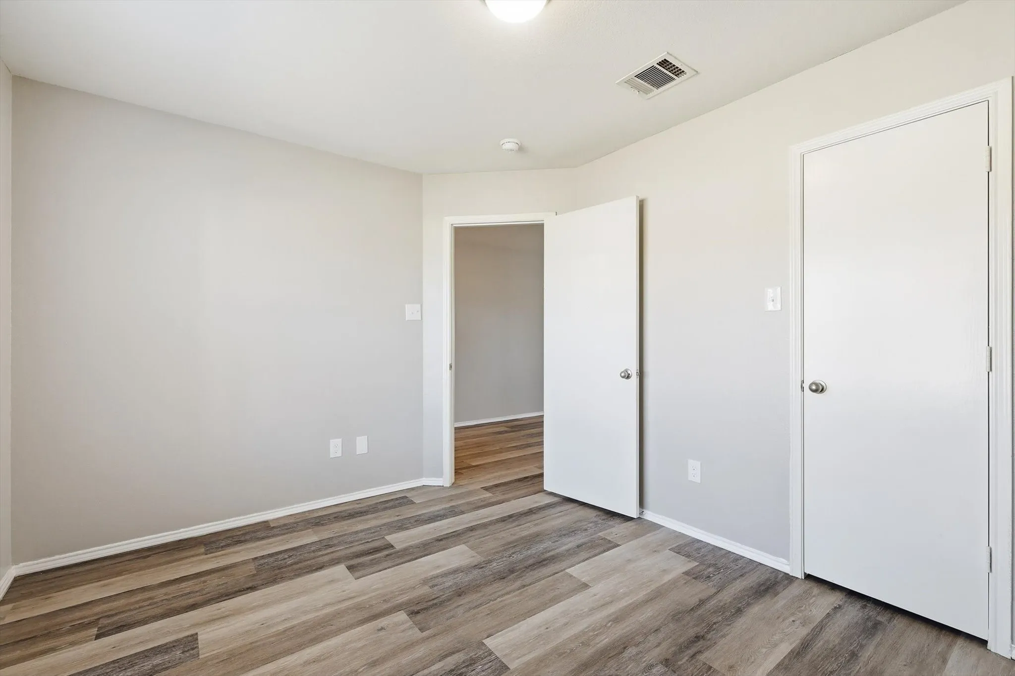 Light gray wall paint with white trim, wood-finish flooring, recessed lighting, and white interior doors