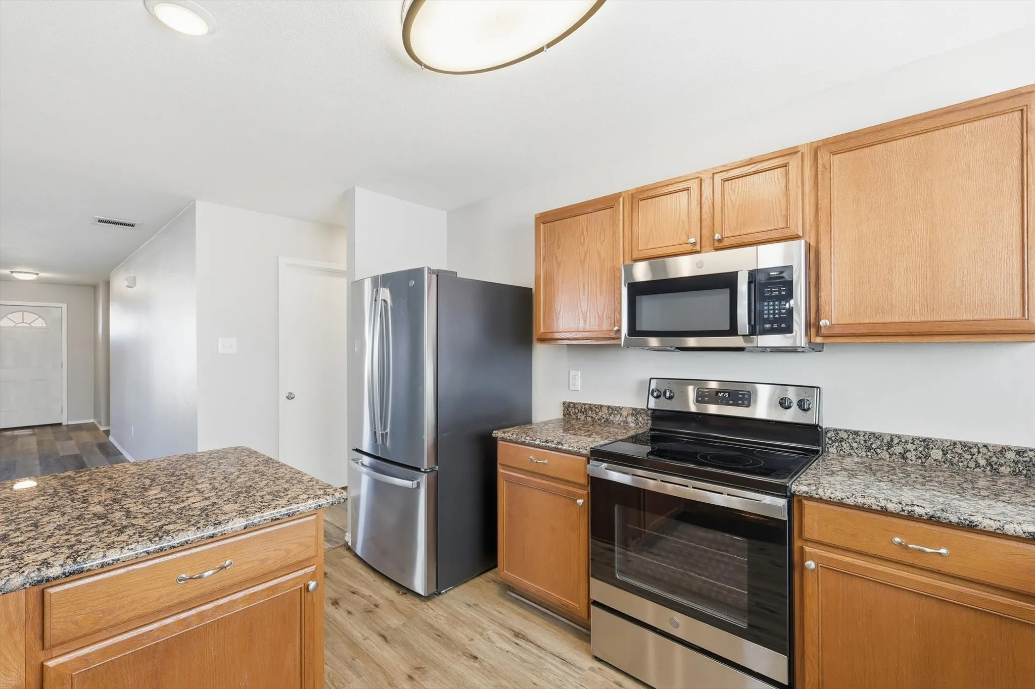 Kitchen featuring wood-finish cabinetry, stone-finish countertops, and stainless steel appliances