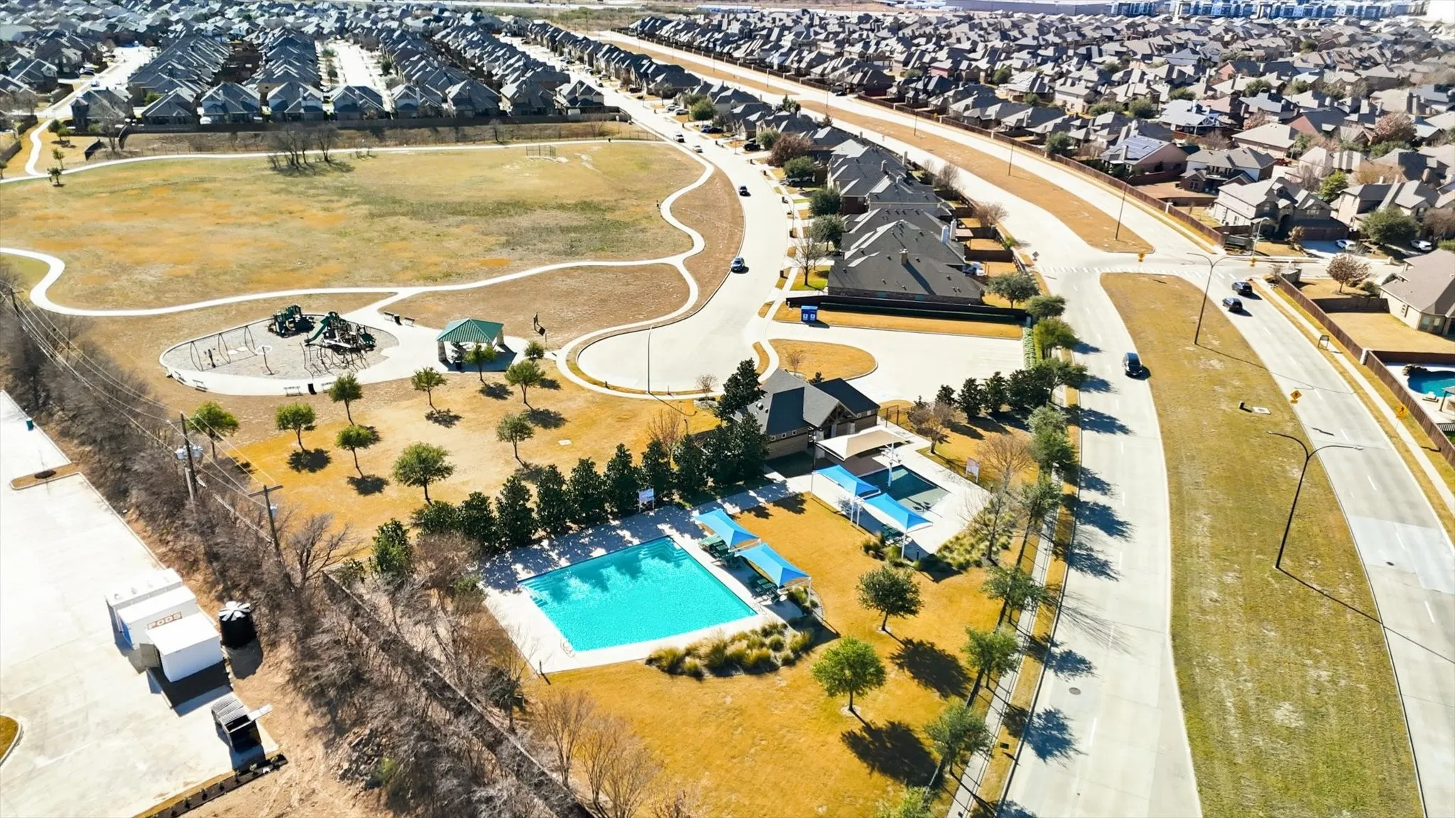 Community amenities featuring a swimming pool, shaded lounge areas, a playground, and a large open field with walking paths
