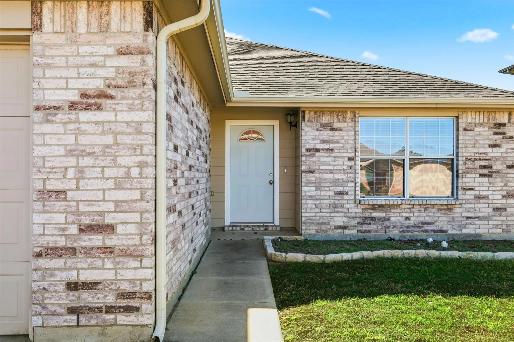 Brick exterior with a gabled roof and concrete walkway