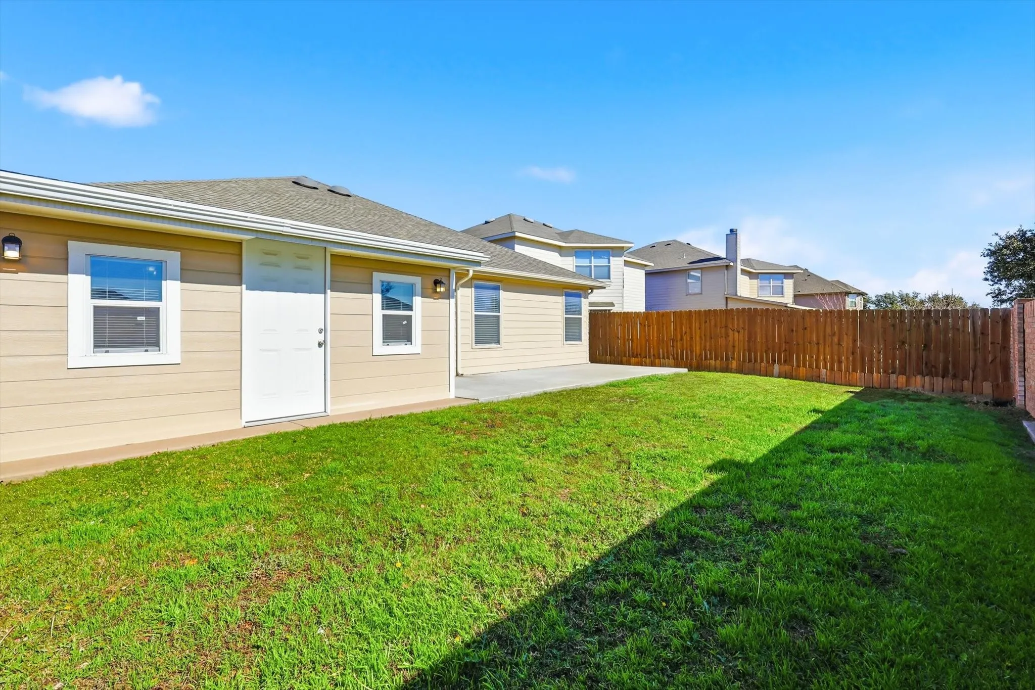 Expansive green lawn with a wood plank privacy fence and brick fence