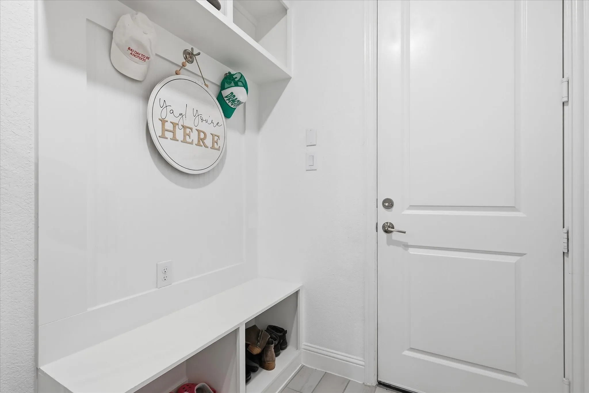 Built-in bench with integrated shelving, overhead shelf, wall paneling, and a solid core door