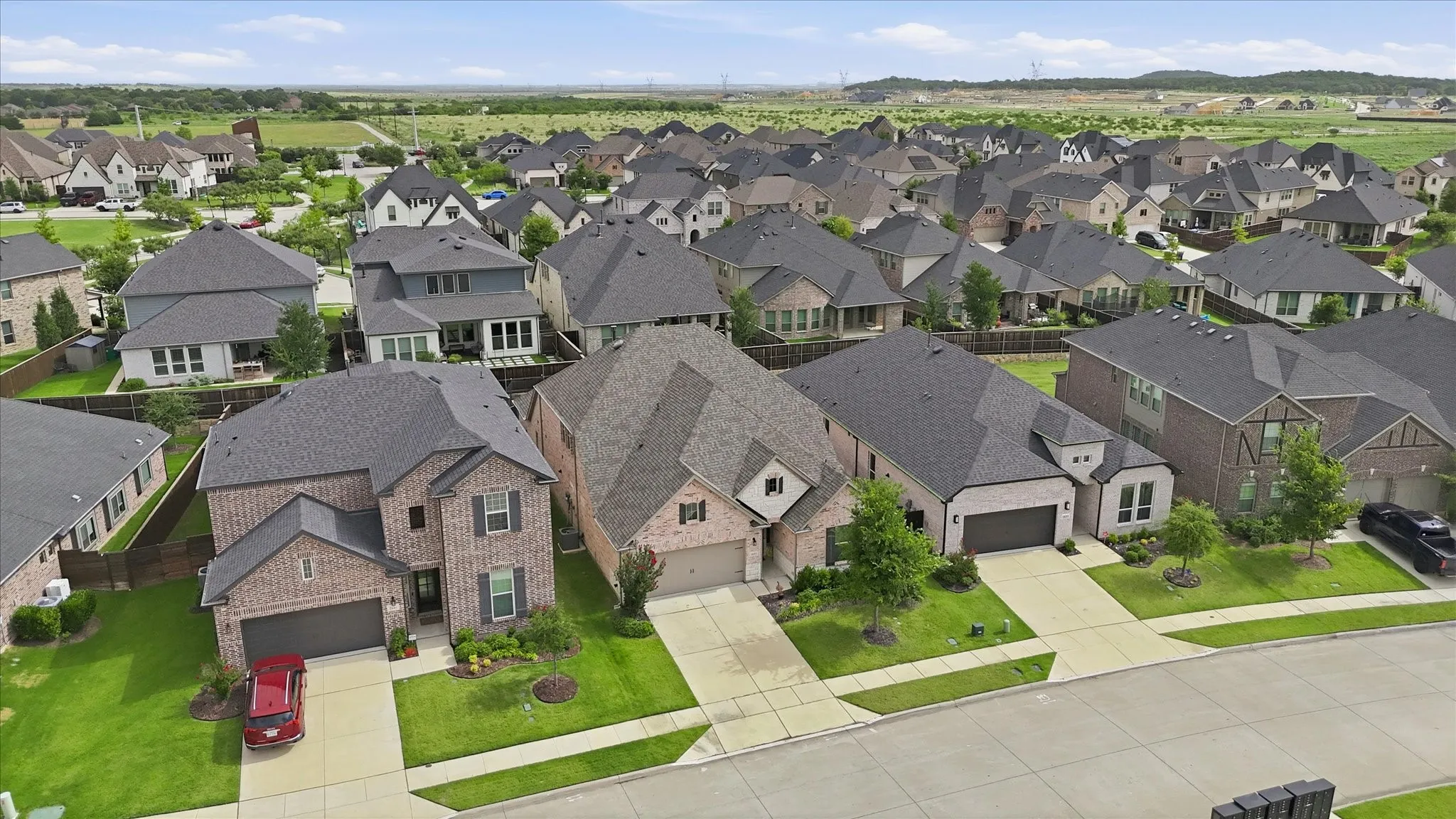 Residential neighborhood featuring multiple single-family homes with brick and siding exteriors, attached garages, and paved driveways