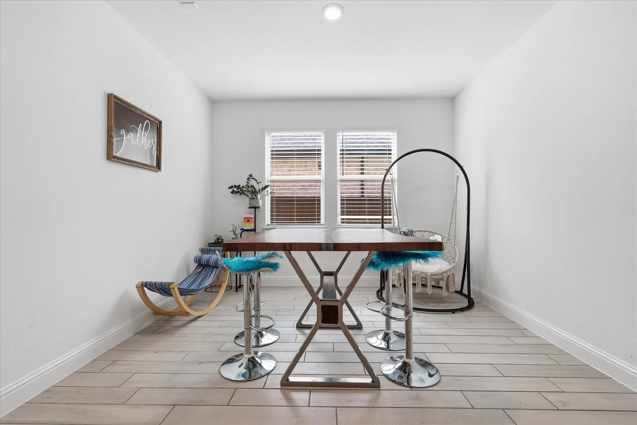 Recessed ceiling lighting, two windows with blinds, wood-finish plank flooring, and crisp white walls