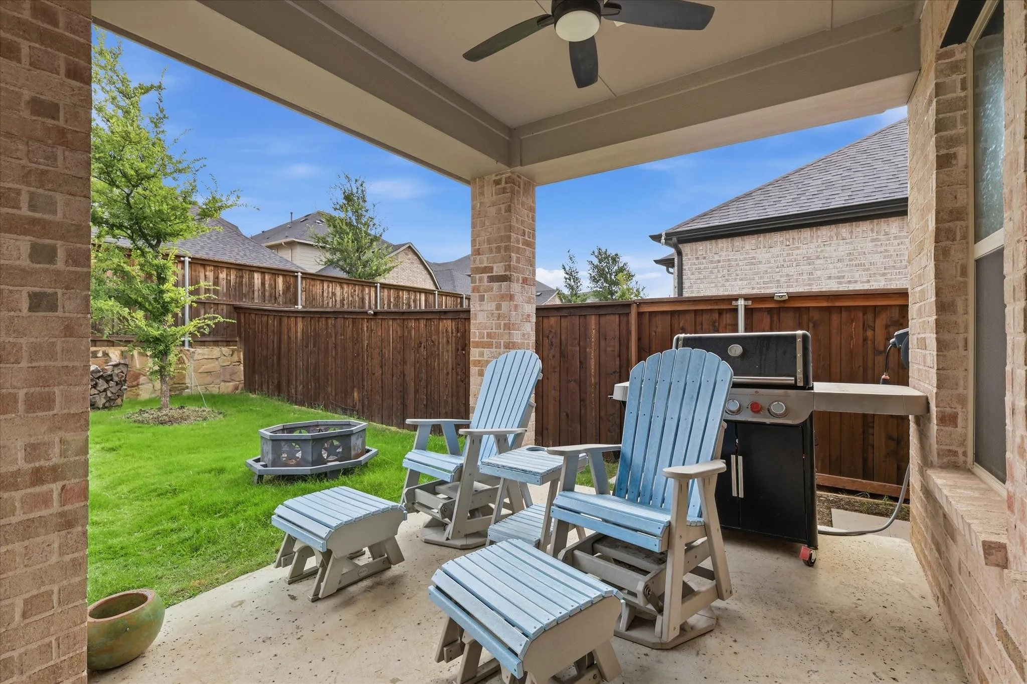 Covered patio featuring a ceiling fan, brick pillars, concrete flooring, and a privacy fence