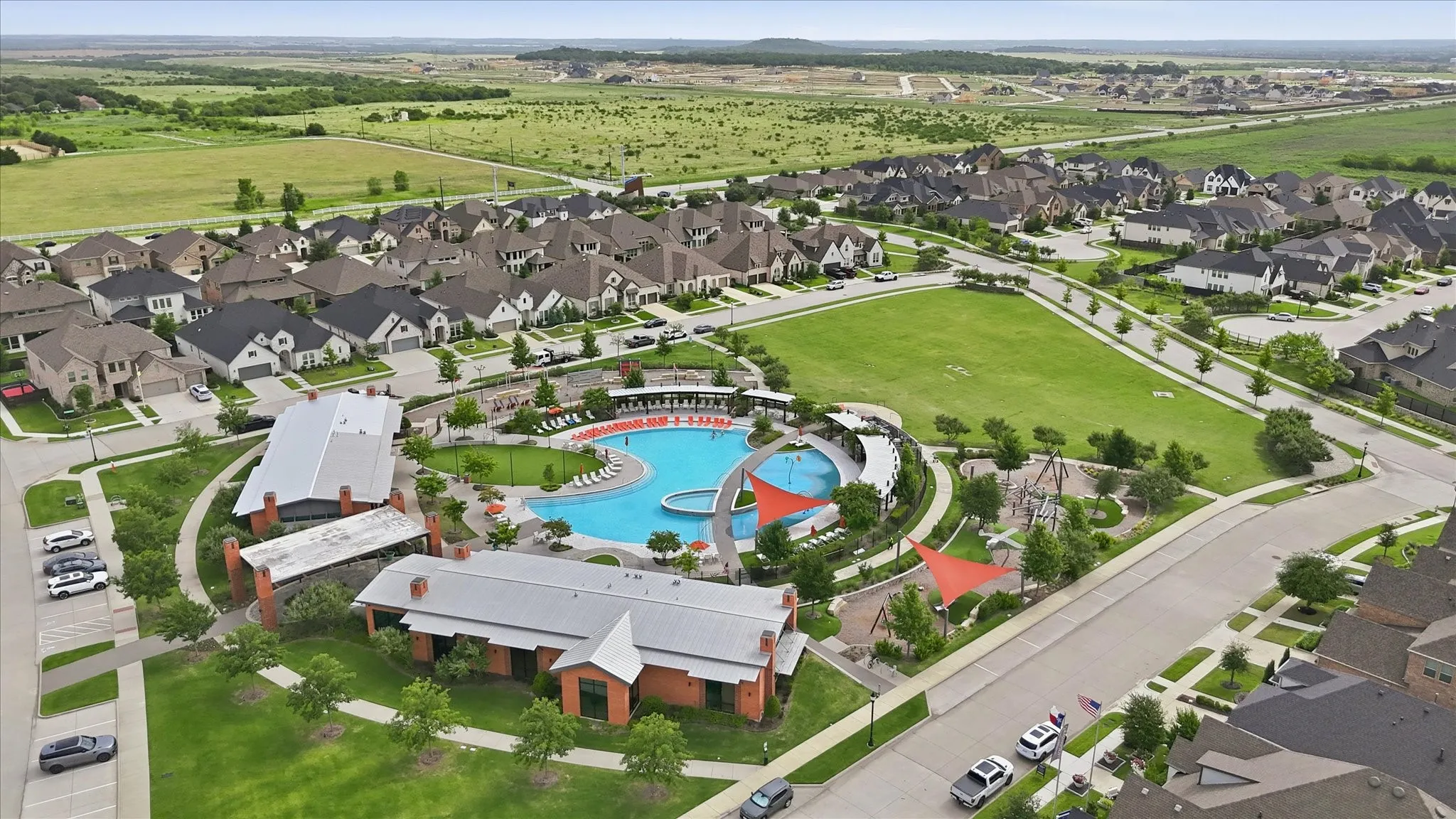 Expansive community with varied architectural styles, a large swimming pool, and a dedicated park area