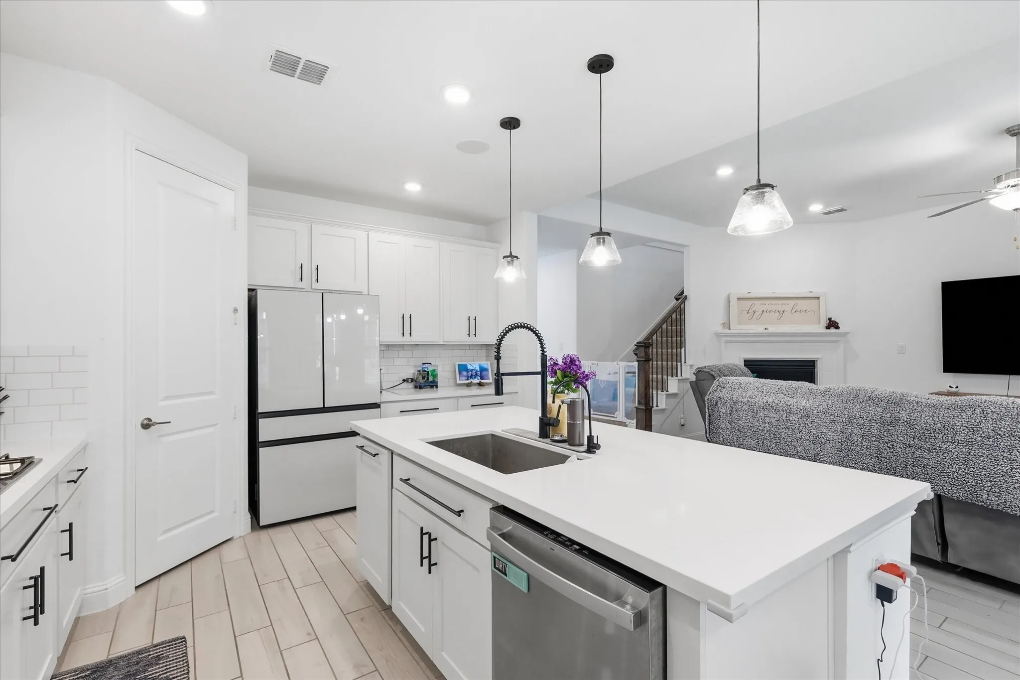 Kitchen with white cabinetry, stainless steel appliances, a center island with sink, and light wood-finish flooring