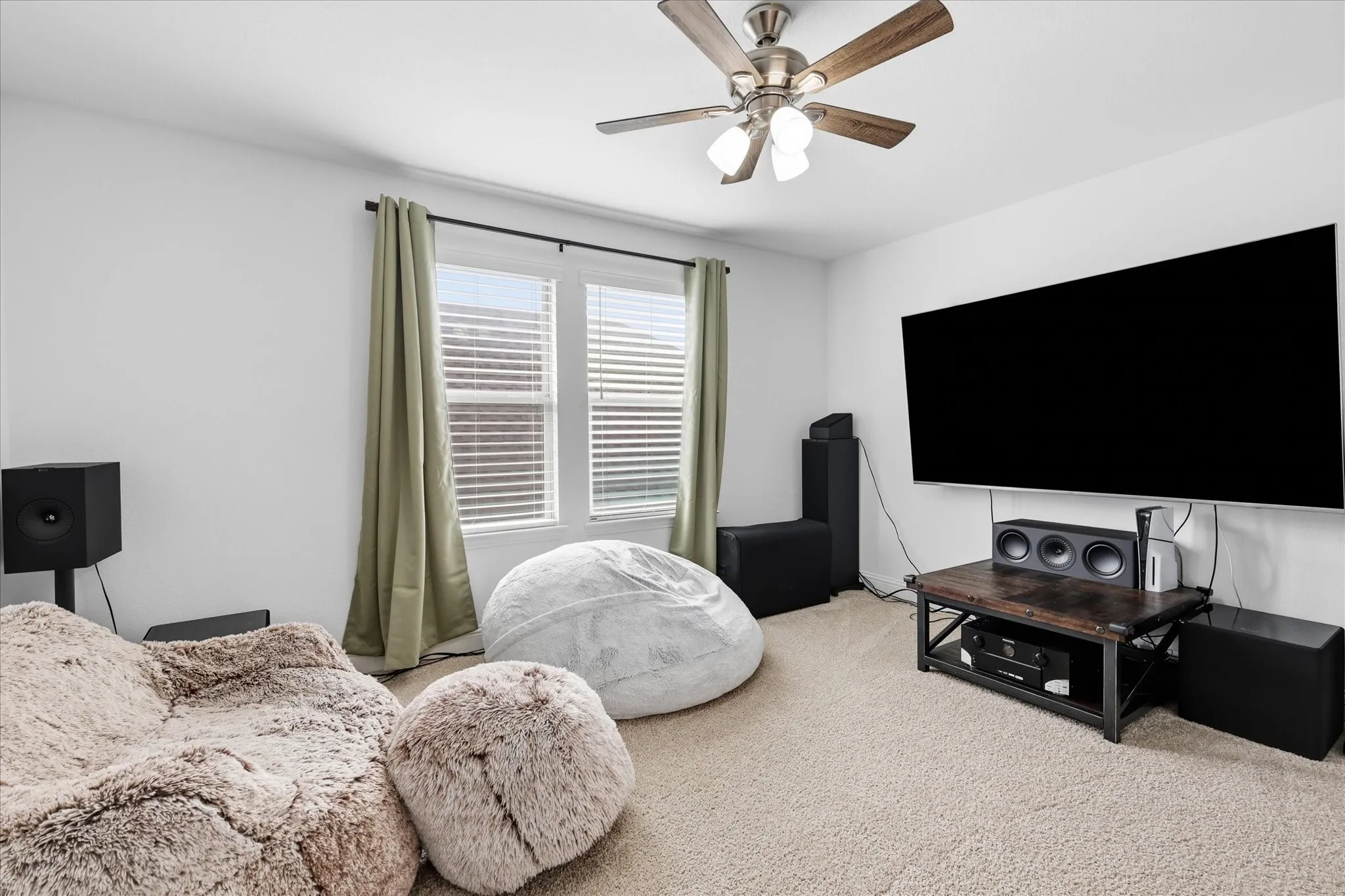 Carpeted flooring, window with blinds and drapes, ceiling fan, and wall-mounted television