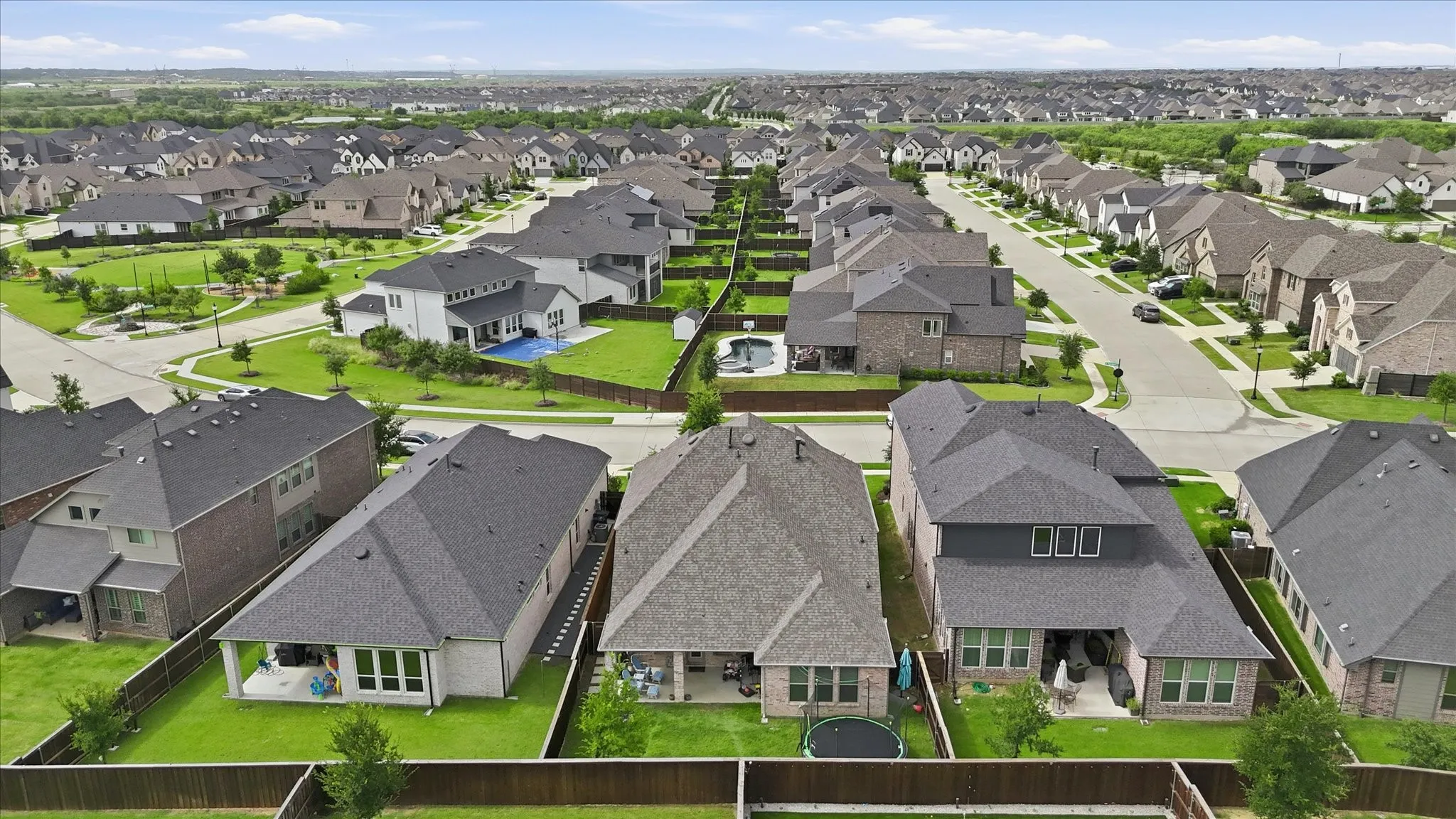 Expansive residential community featuring a variety of architectural styles, individual fenced yards, paved streets, and abundant green spaces