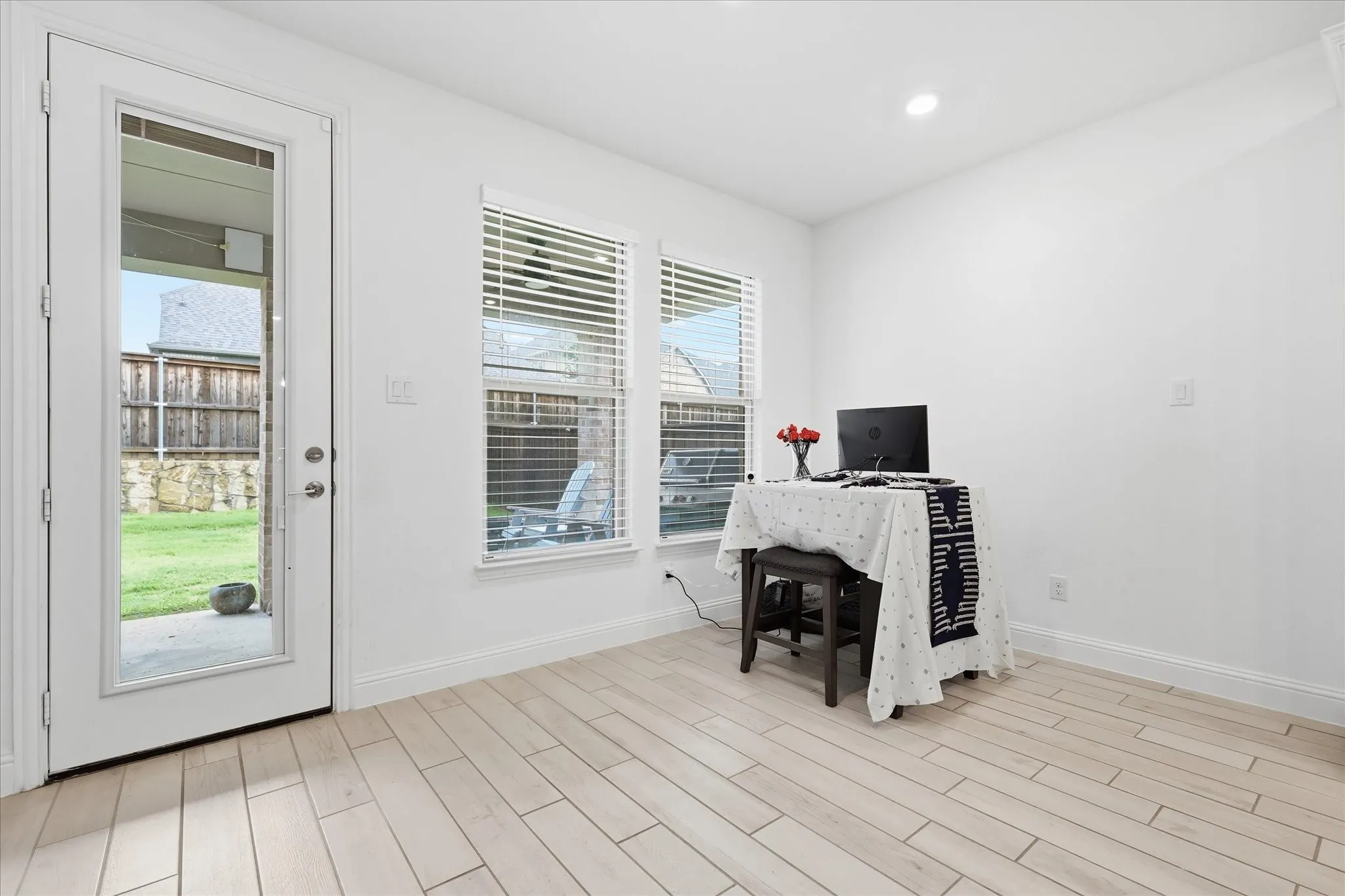 Light wood-finish flooring, white walls, and a glass-paneled exterior door