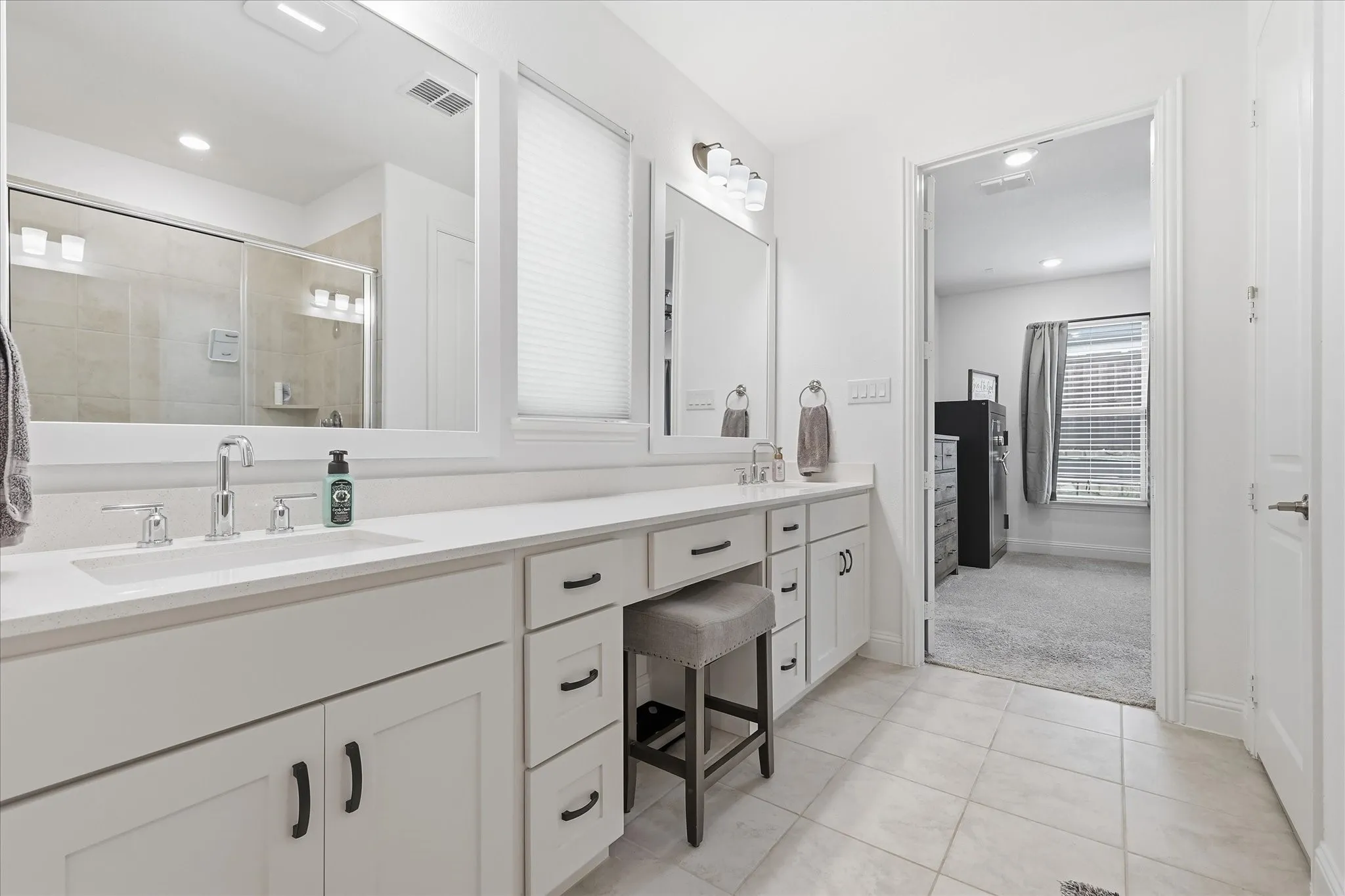 Dual vanity with white cabinetry and dark hardware, integrated sinks, and ample counter space