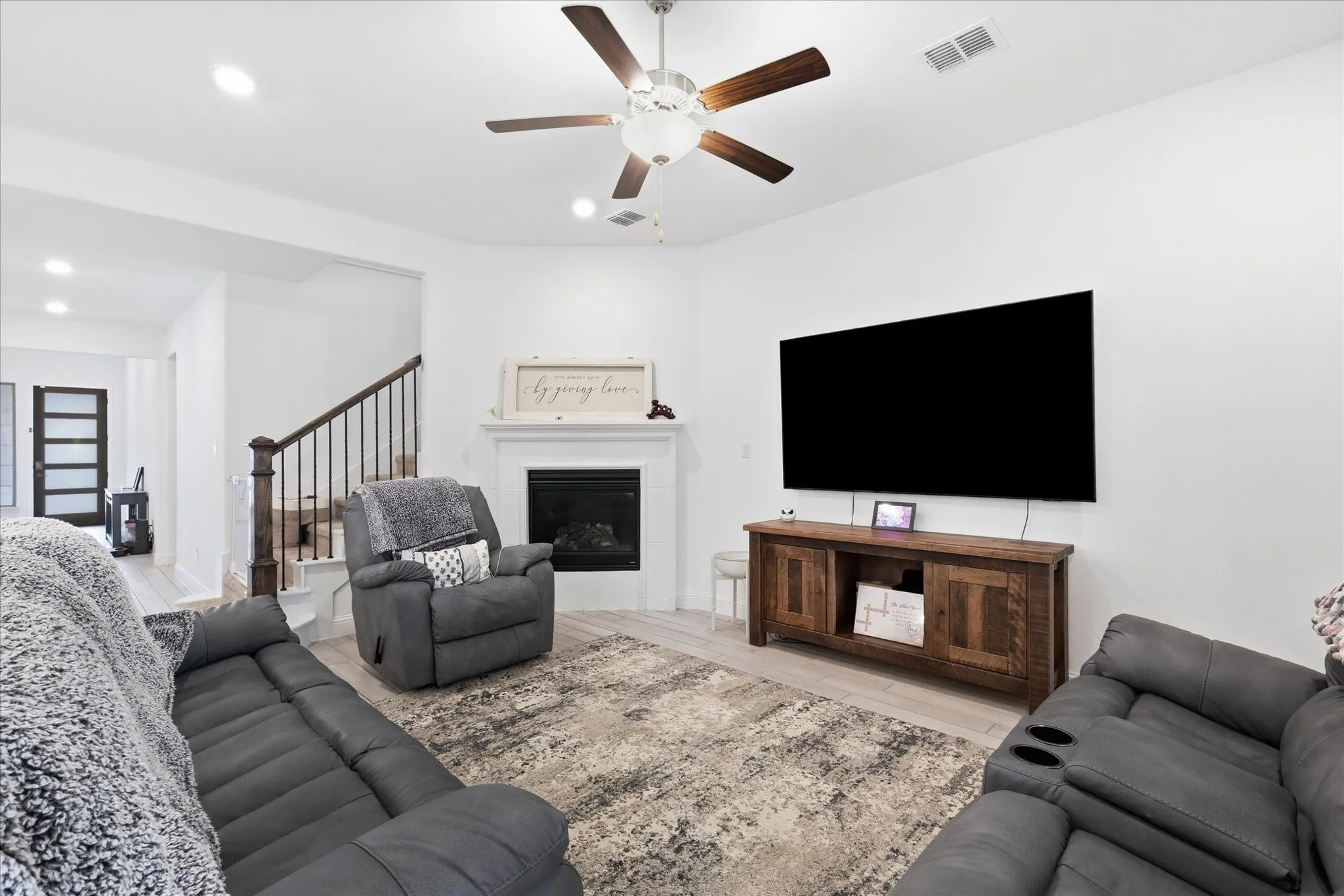 Living area featuring a fireplace with a mantel, wood-finish flooring, and a ceiling fan